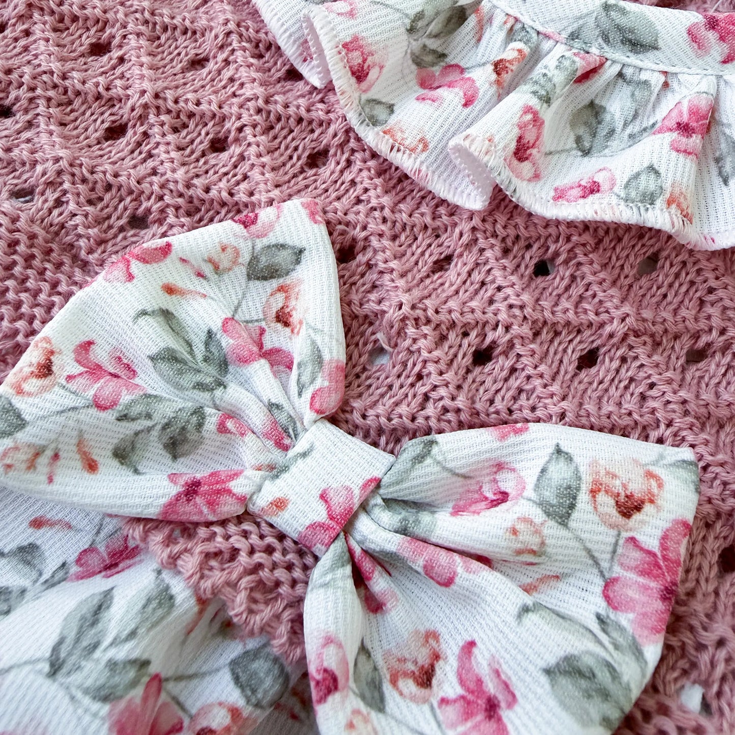 Detalhe de fofo de menina de padrão florido com folho na gola e laço na frente