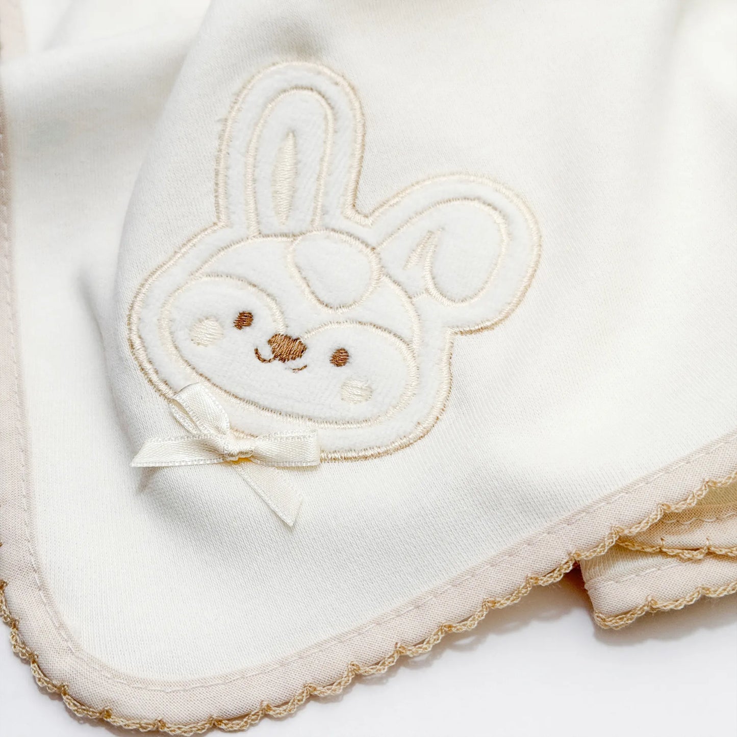 Pormenor de fralda com motivo coelho em relevo pérola