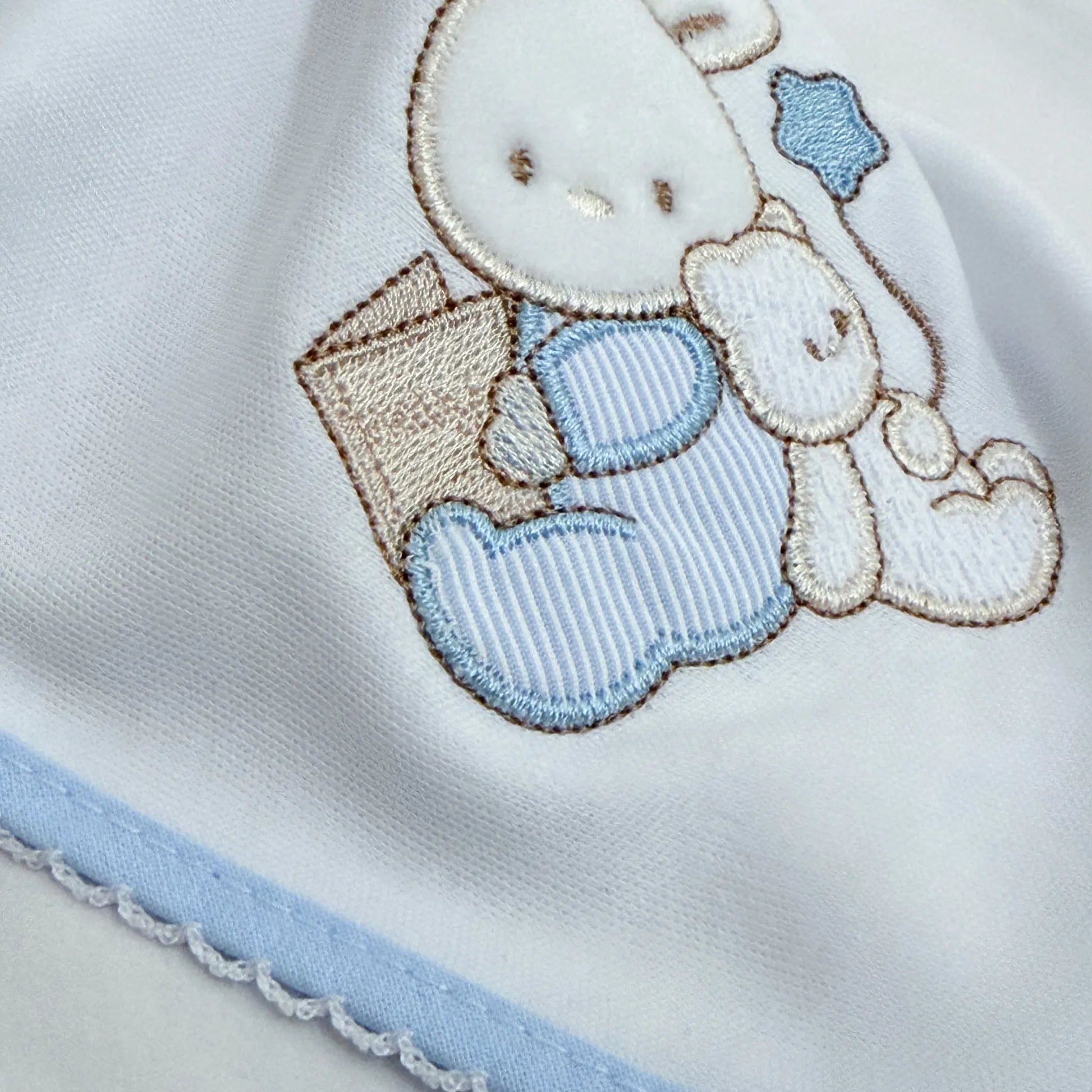 Pormenor de fralda com motivo coelhinho e ursinho com livro azul