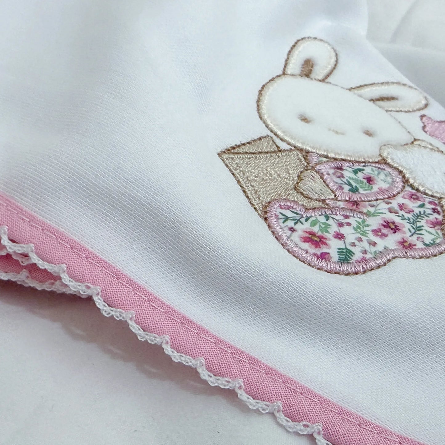 Pormenor de fralda com motivo coelhinho e ursinho com livro rosa