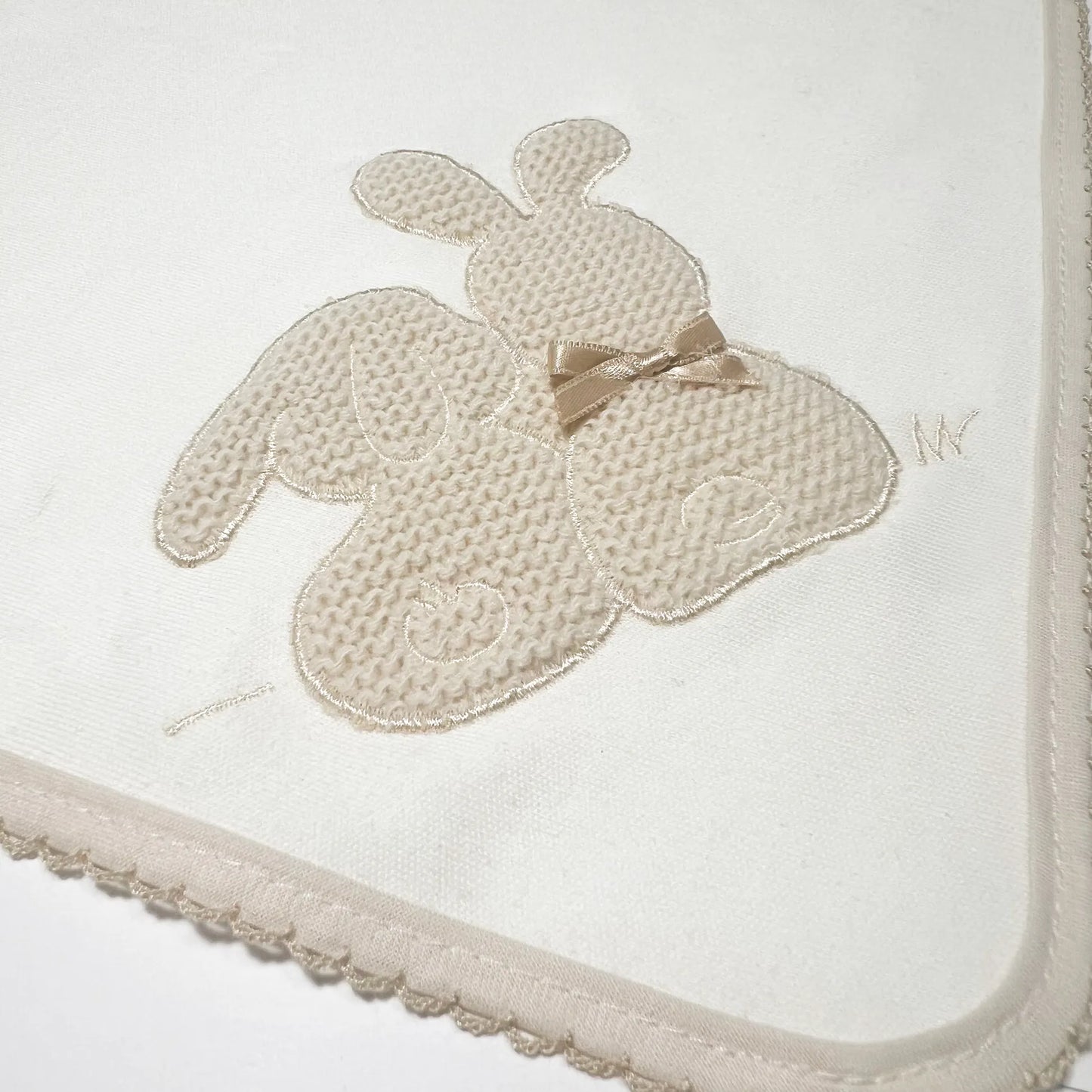 Pormenor de fralda com motivo coelhos tricot com lacinho pérola