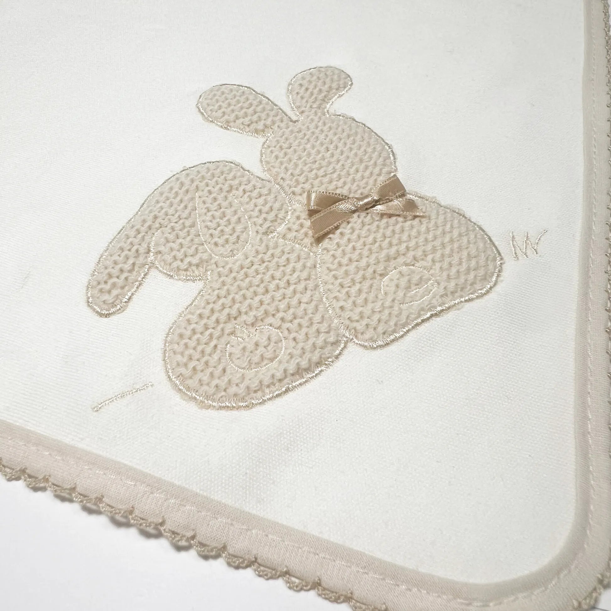 Pormenor de fralda com motivo coelhos tricot com lacinho pérola