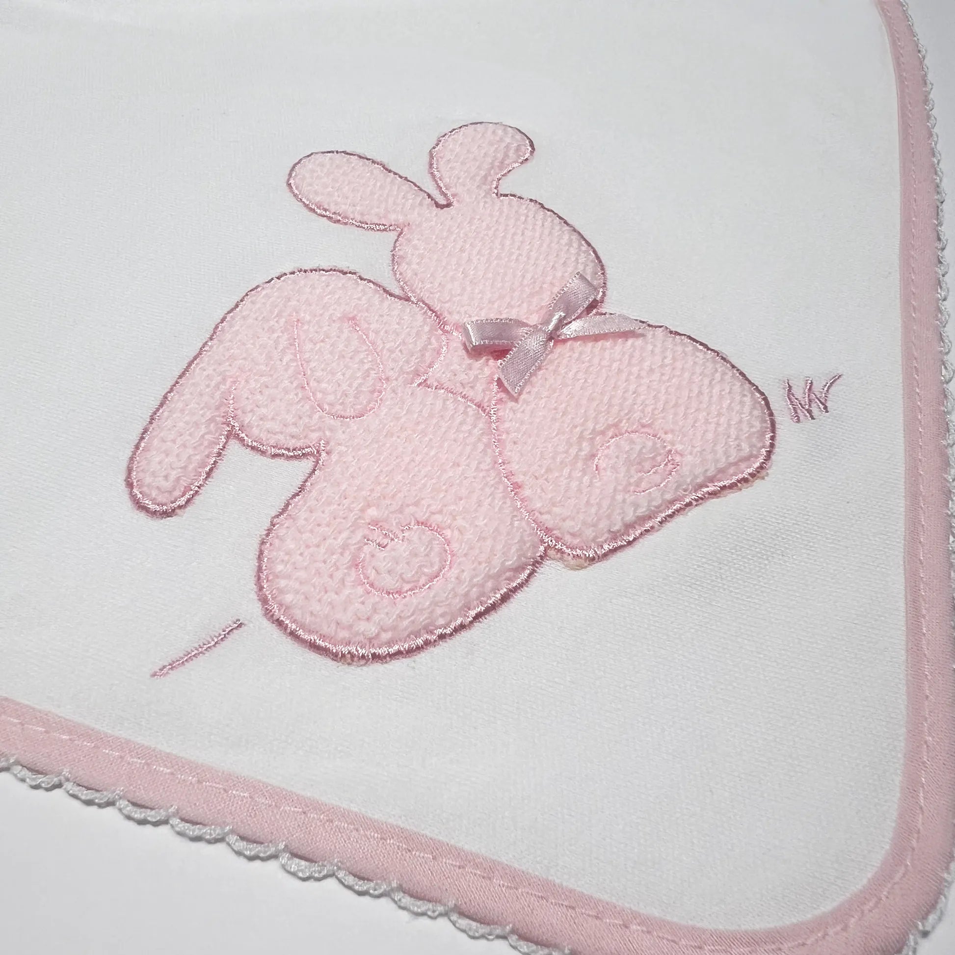 Pormenor de fralda com motivo coelhos tricot com lacinho rosa