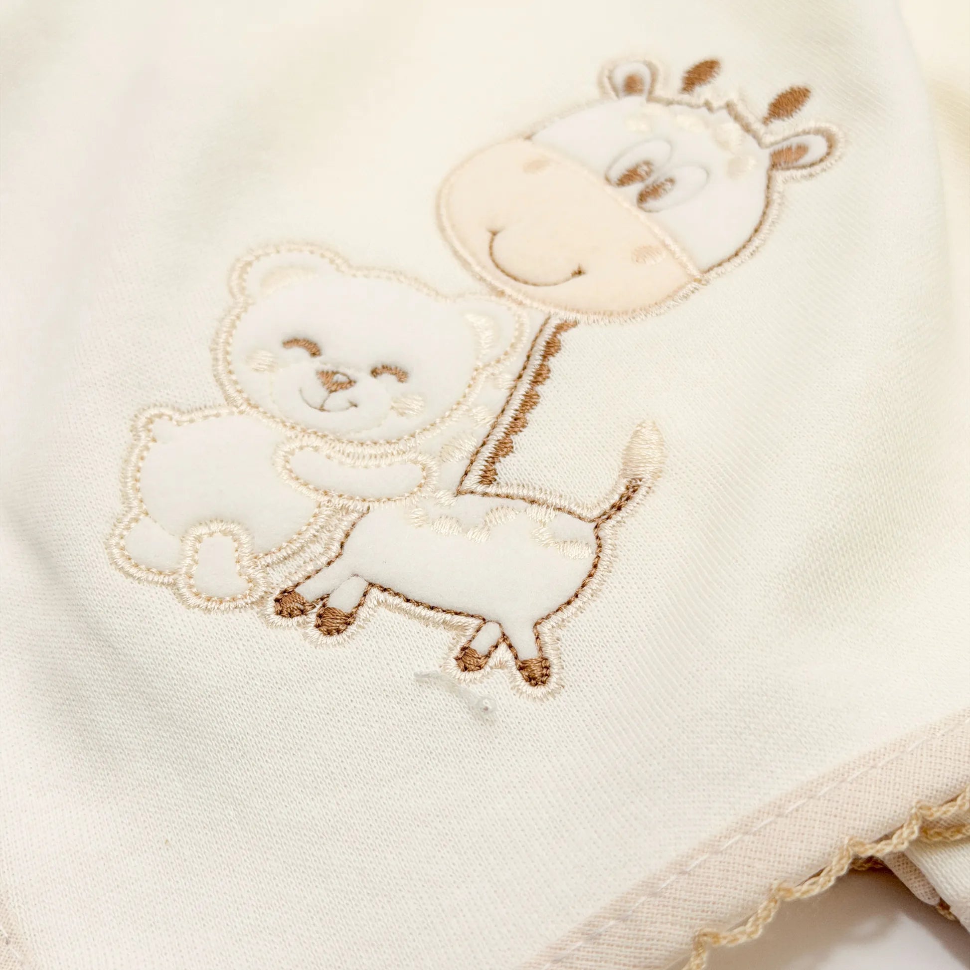 Pormenor de fralda com motivo girafa e ursinho pérola