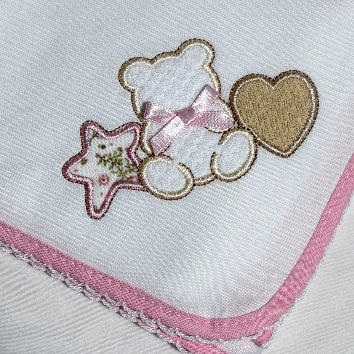 Pormenor de fralda com motivo ursinho entre estrela e coração rosa