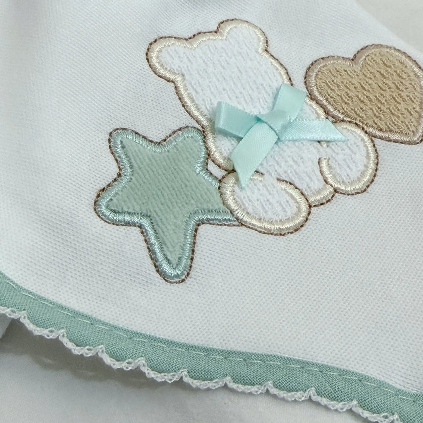 Pormenor de fralda com motivo ursinho entre estrela e coração verde