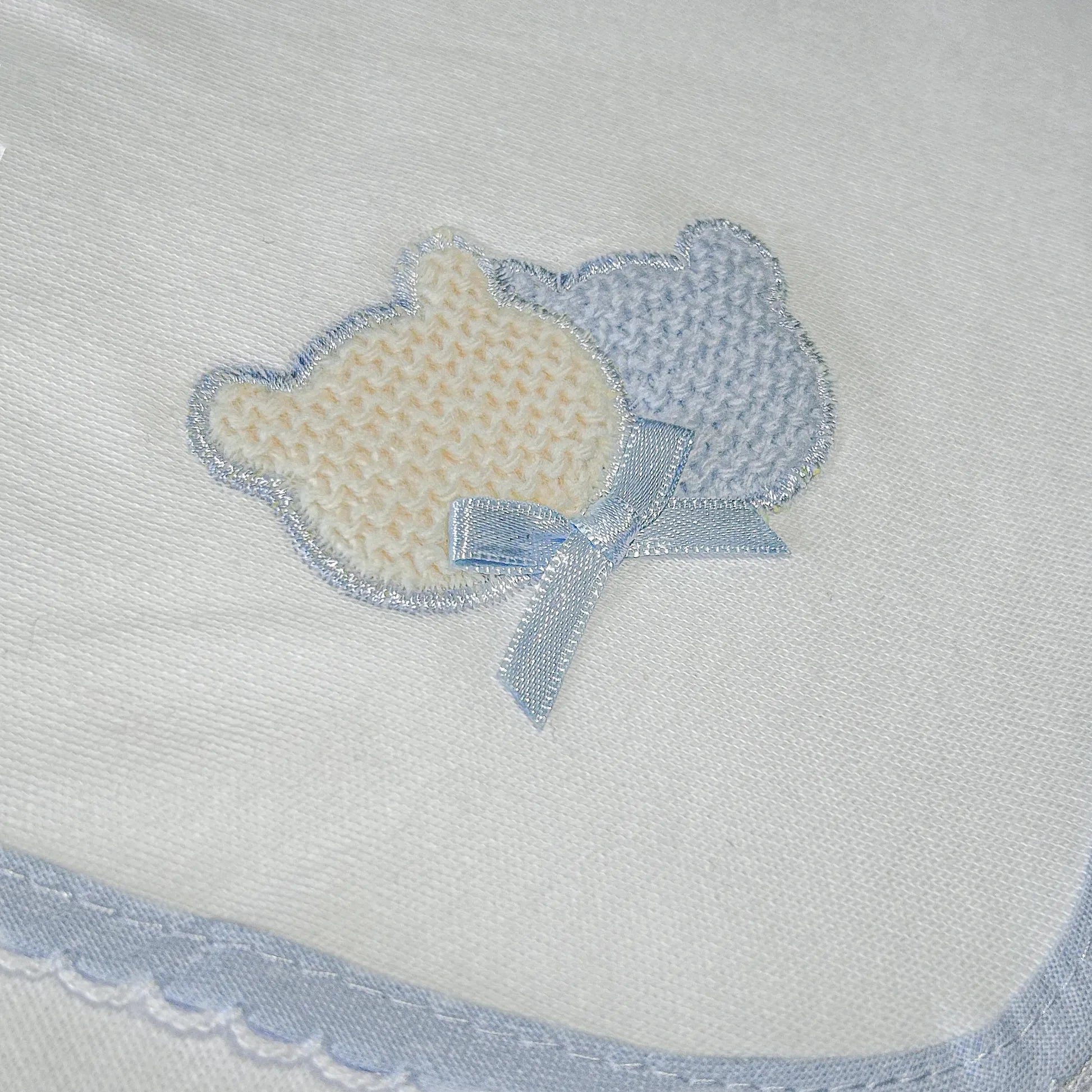 Pormenor de fralda com motivo ursinhos tricot e lacinho azul