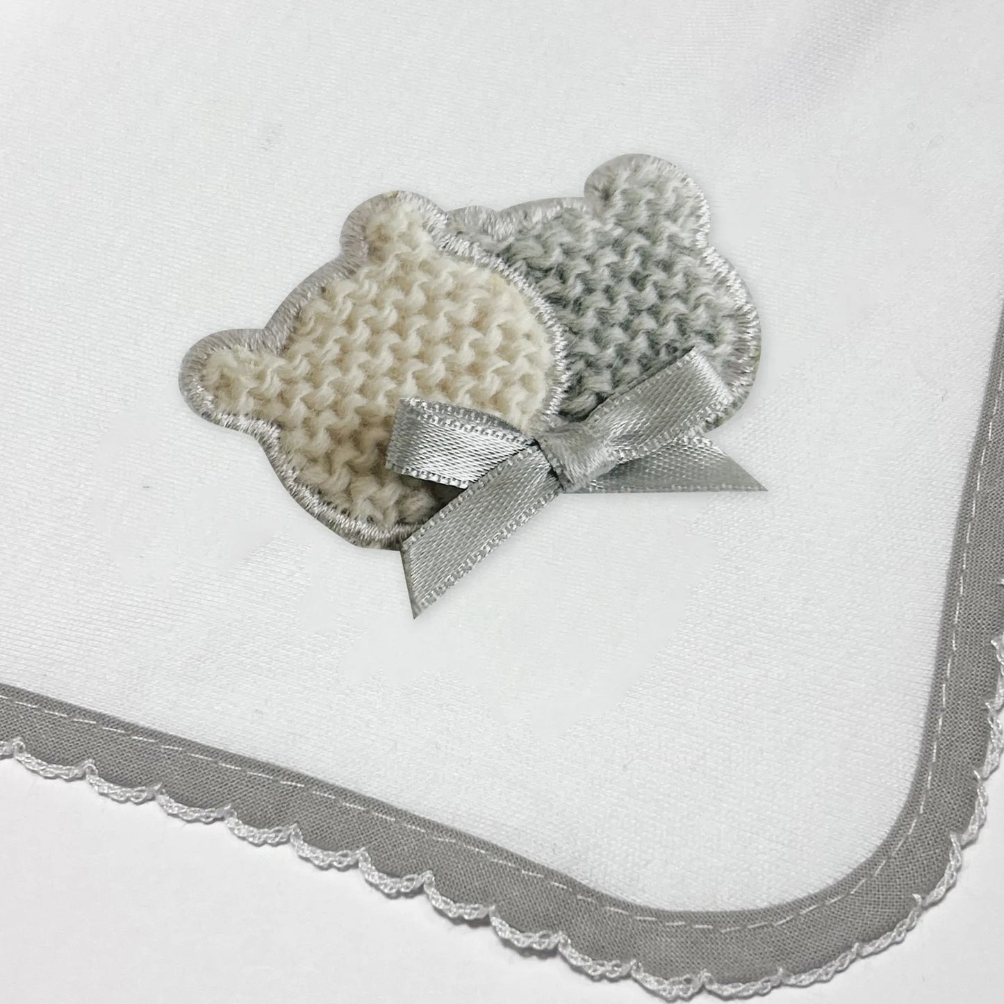 Pormenor de fralda com motivo ursinhos tricot e lacinho cinza
