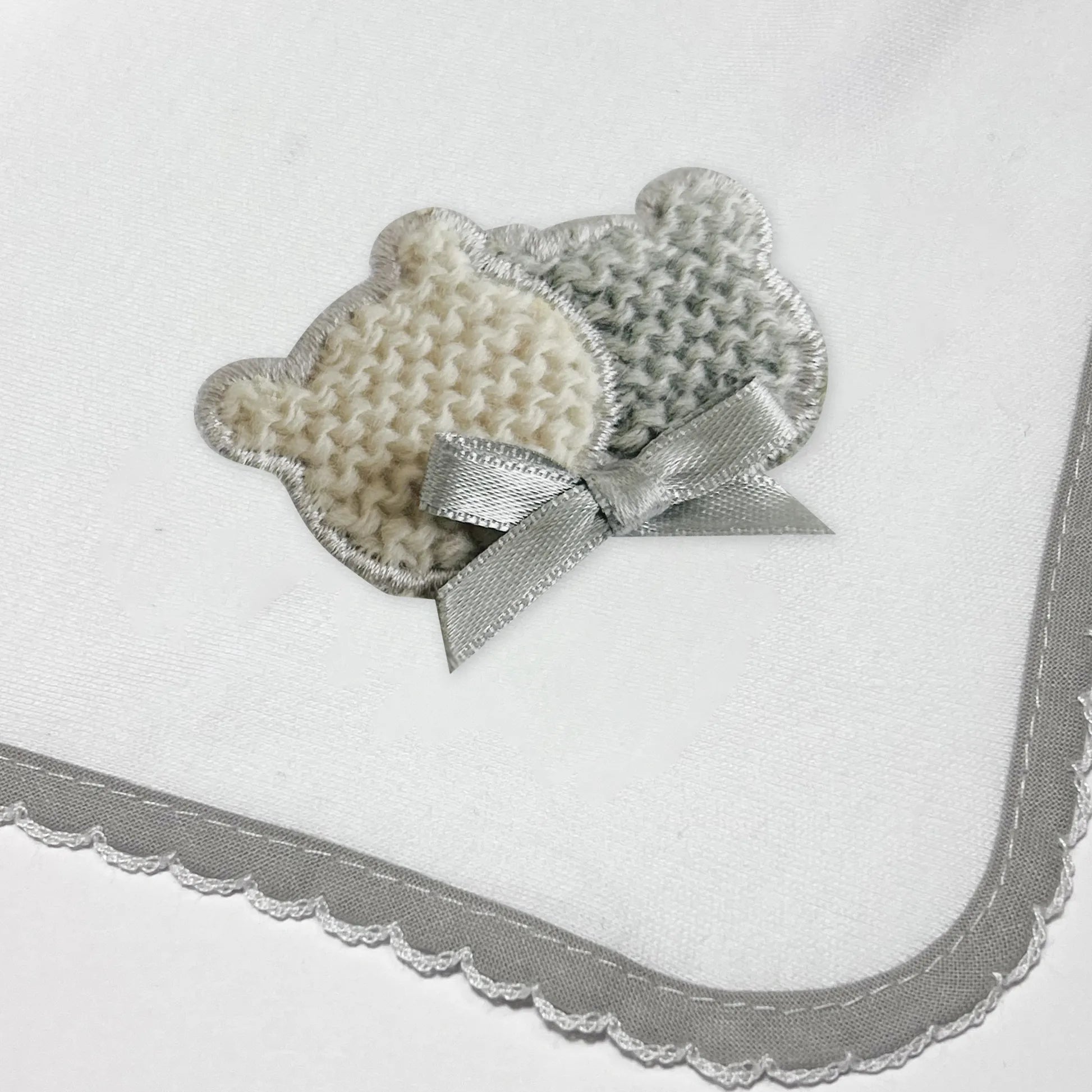 Pormenor de fralda com motivo ursinhos tricot e lacinho cinza