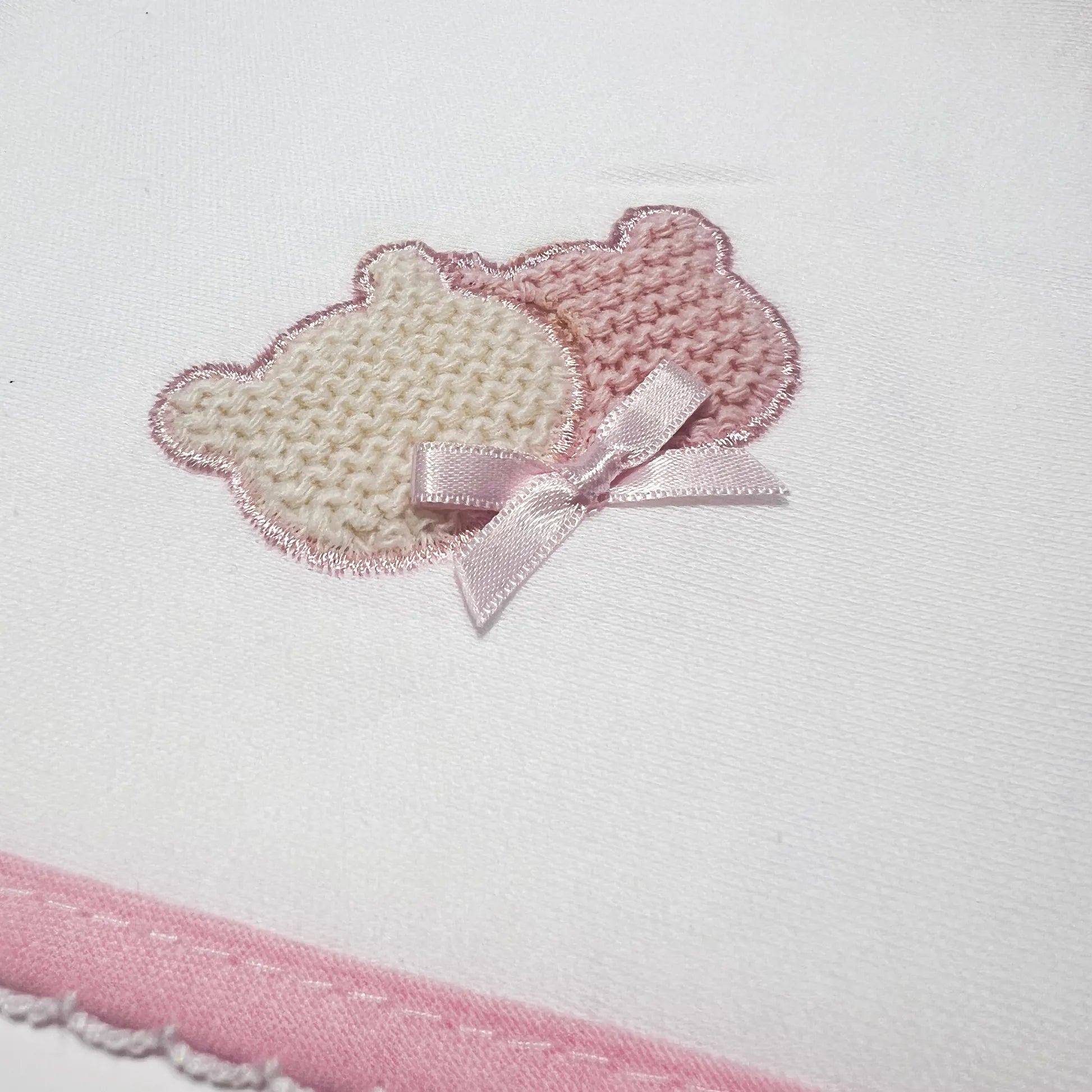 Pormenor de fralda com motivo ursinhos tricot e lacinho rosa