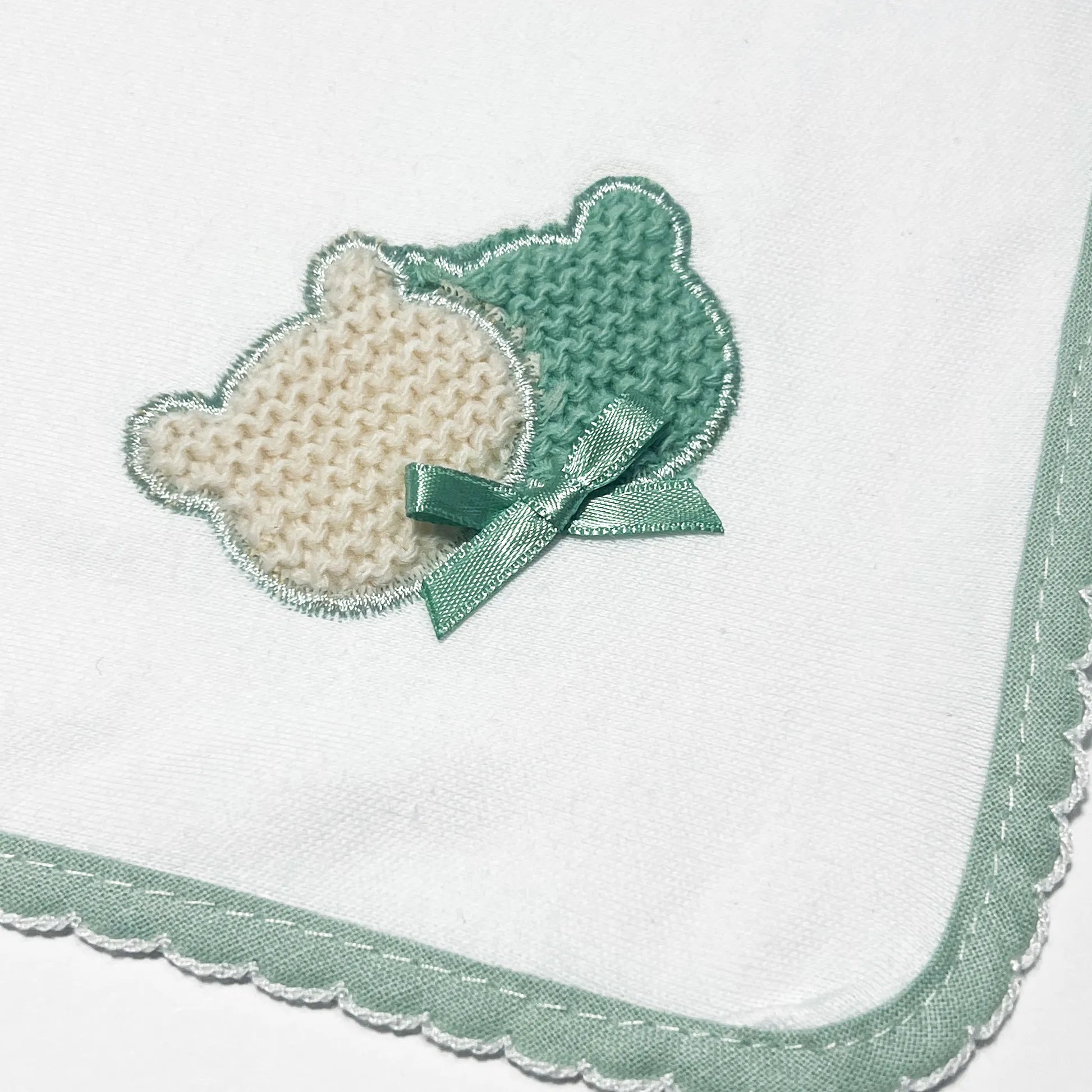 Pormenor de fralda com motivo ursinhos tricot e lacinho verde