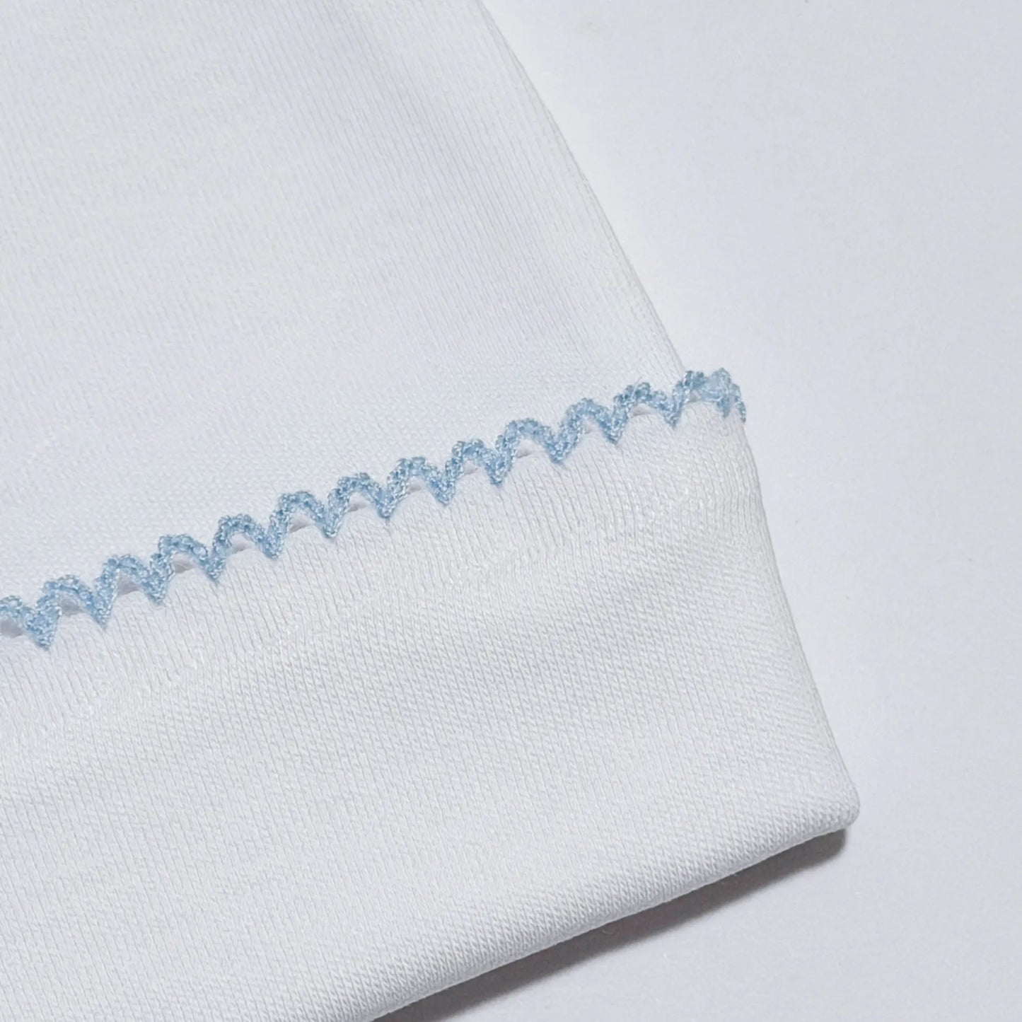 Pormenor de gorro branco com picueta colorida na dobra azul