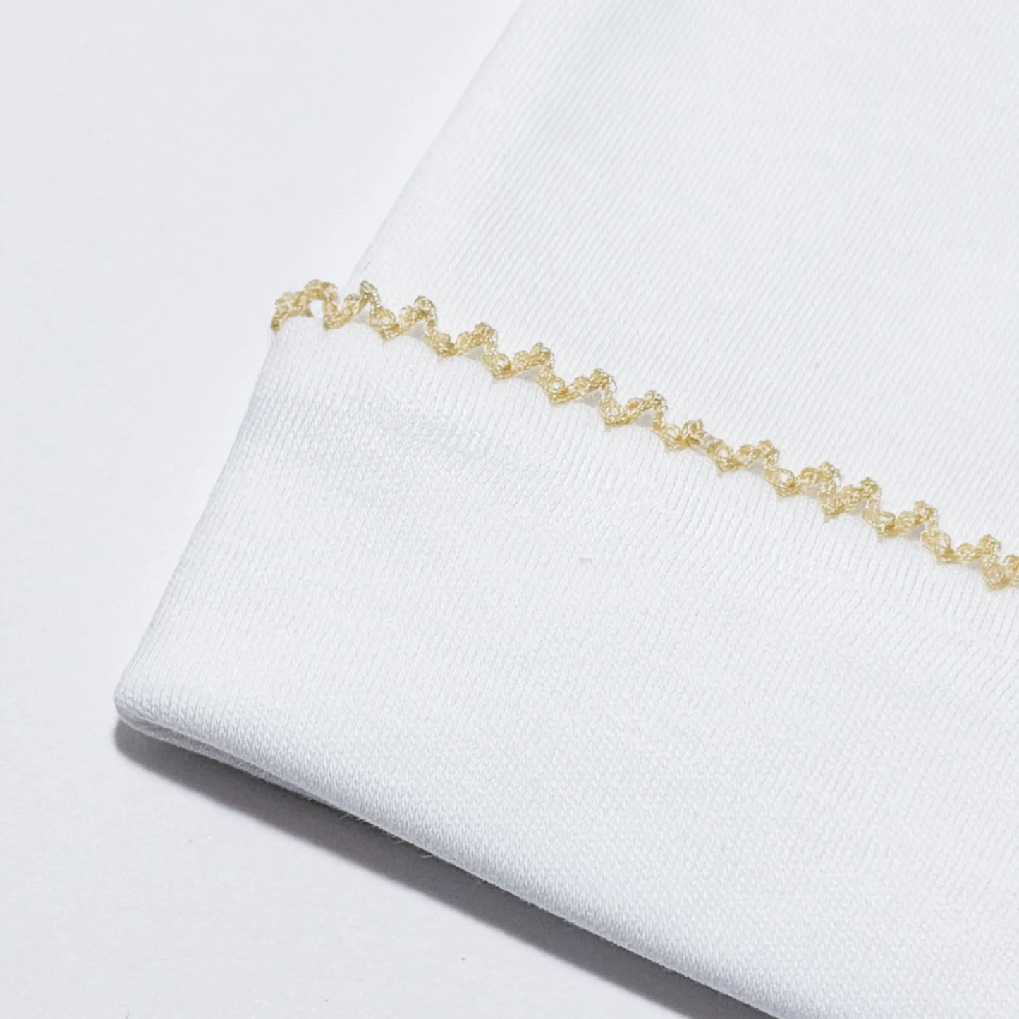 Pormenor de gorro branco com picueta colorida na dobra bege