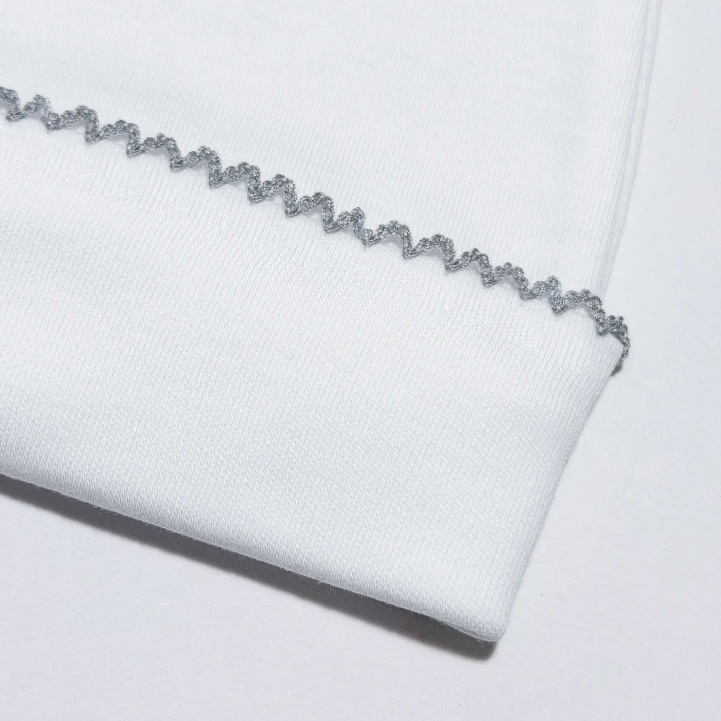 Pormenor de gorro branco com picueta colorida na dobra cinza