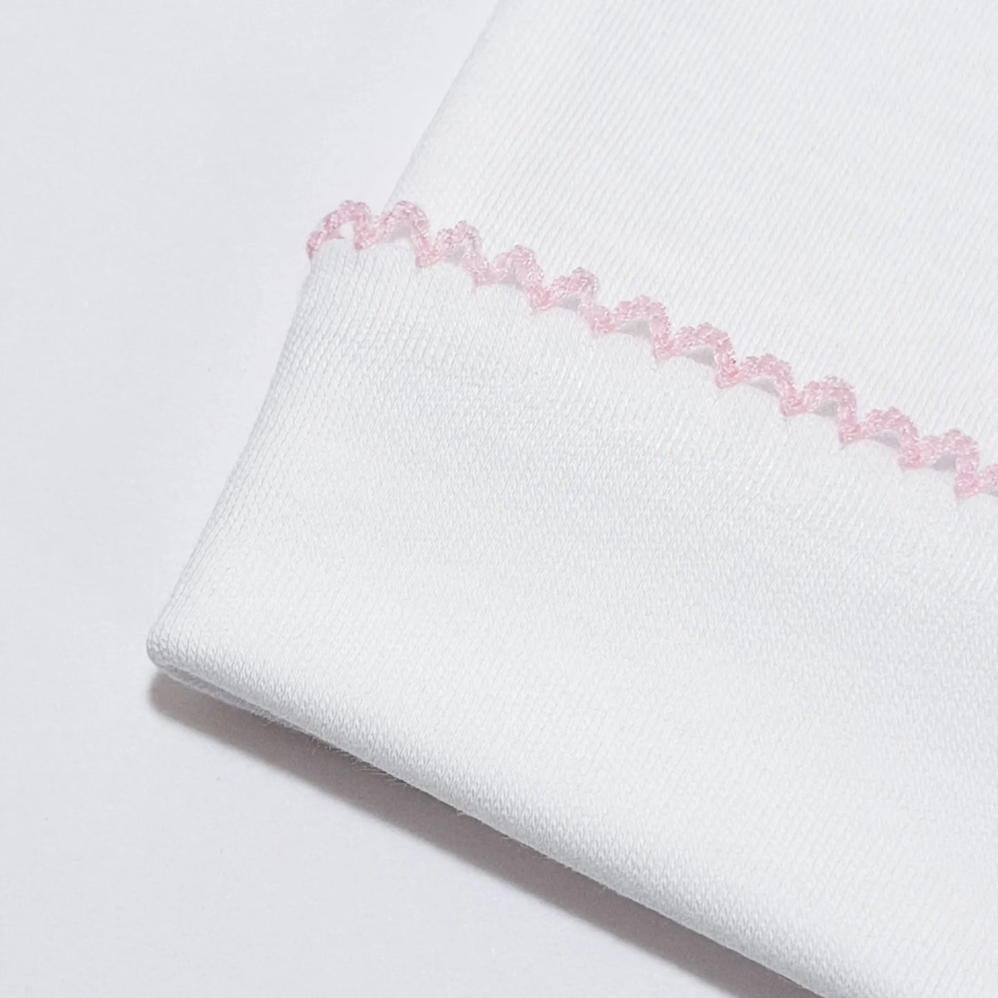 Pormenor de gorro branco com picueta colorida na dobra rosa