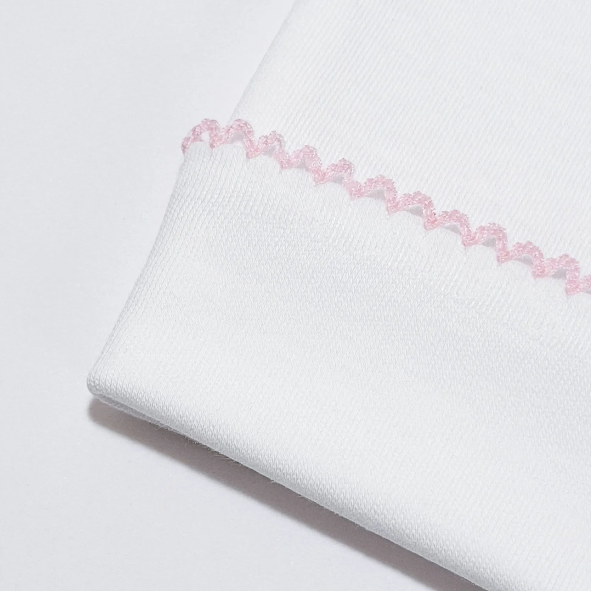 Pormenor de gorro branco com picueta colorida na dobra rosa