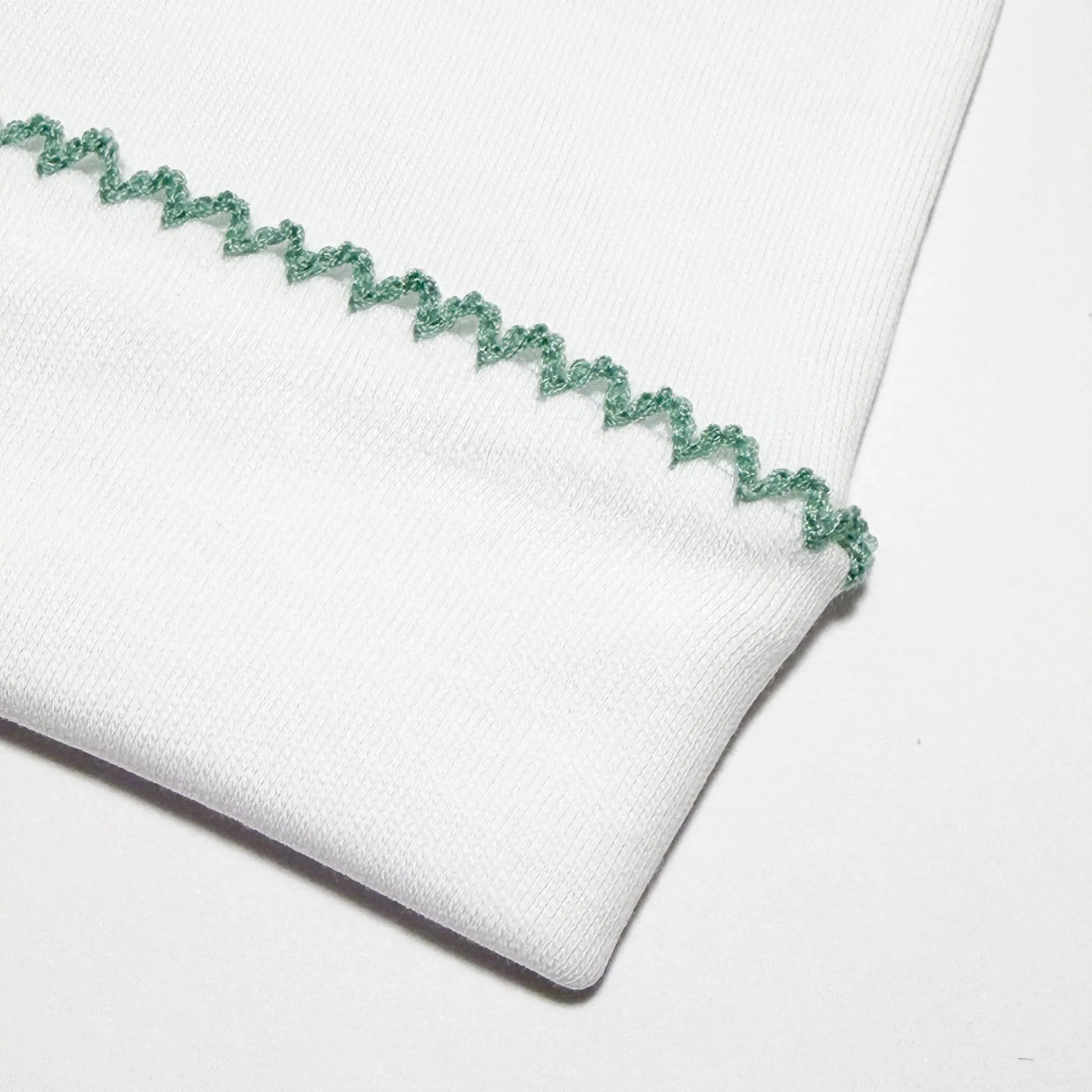 Pormenor de gorro branco com picueta colorida na dobra verde