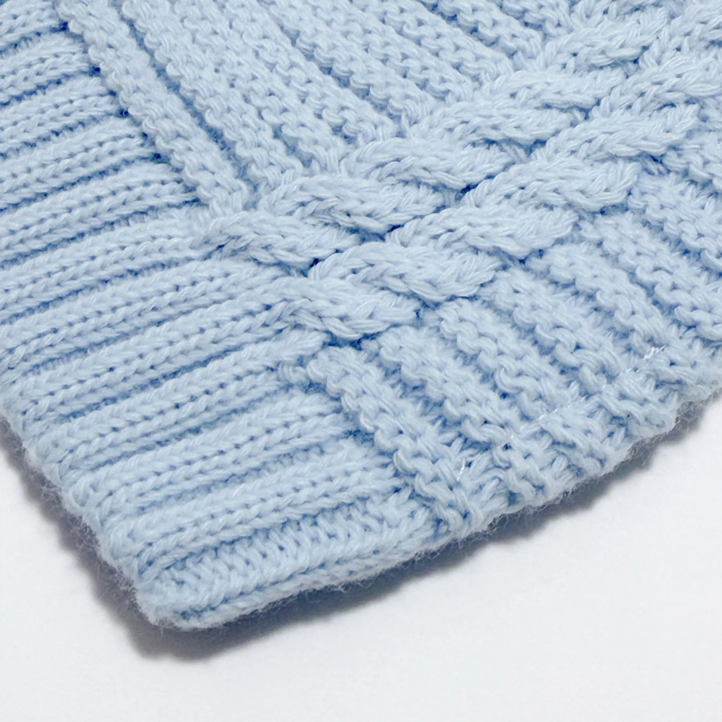 Pormenor de gorro de malha tricotada com pompom azul