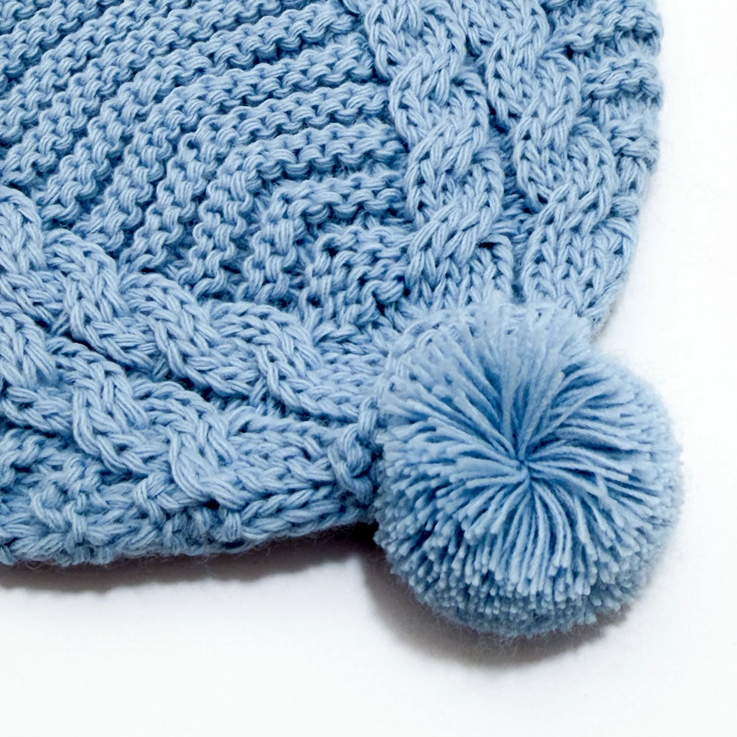 Pormenor de gorro de malha tricotada com pompom cobalto