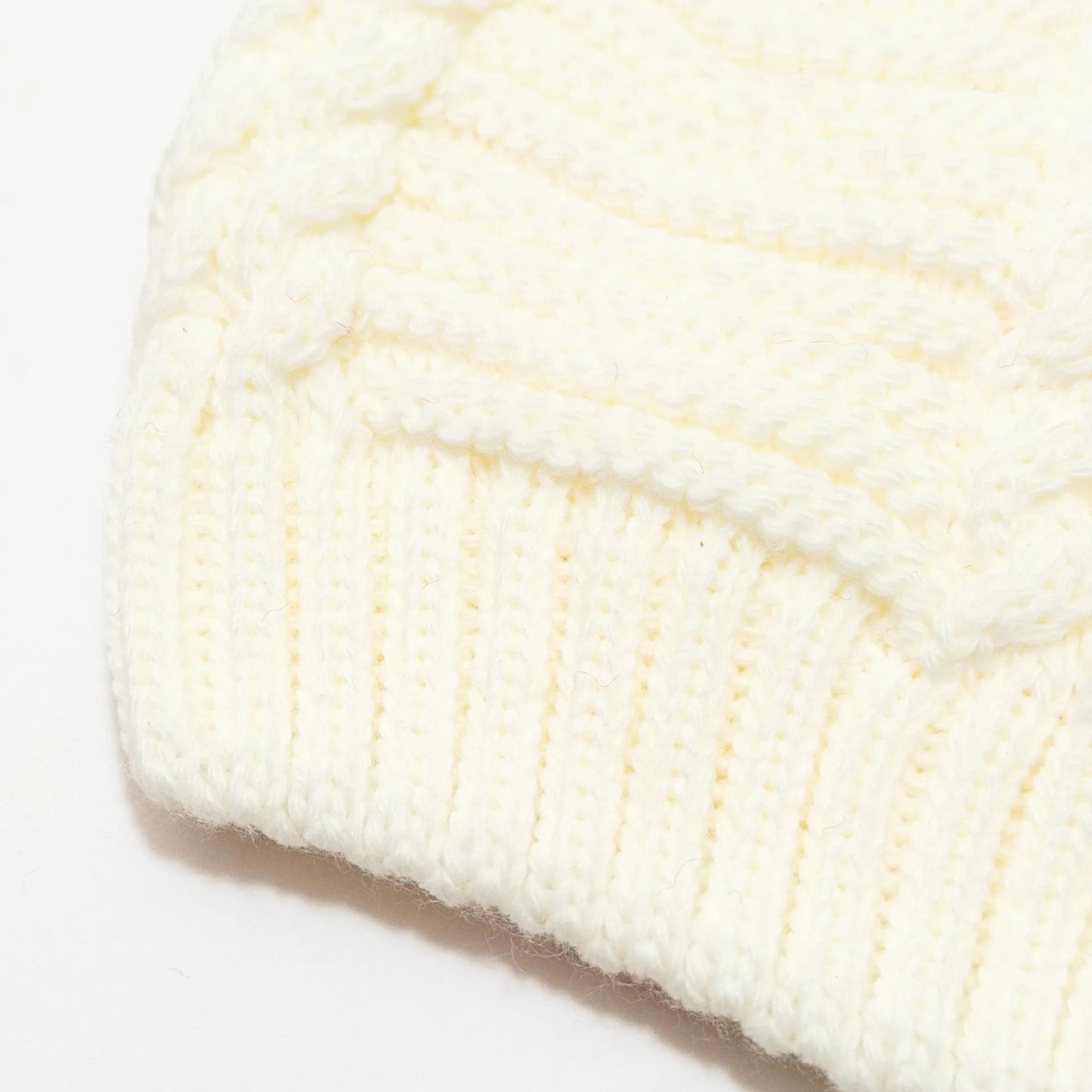 Pormenor de gorro de malha tricotada com pompom pérola