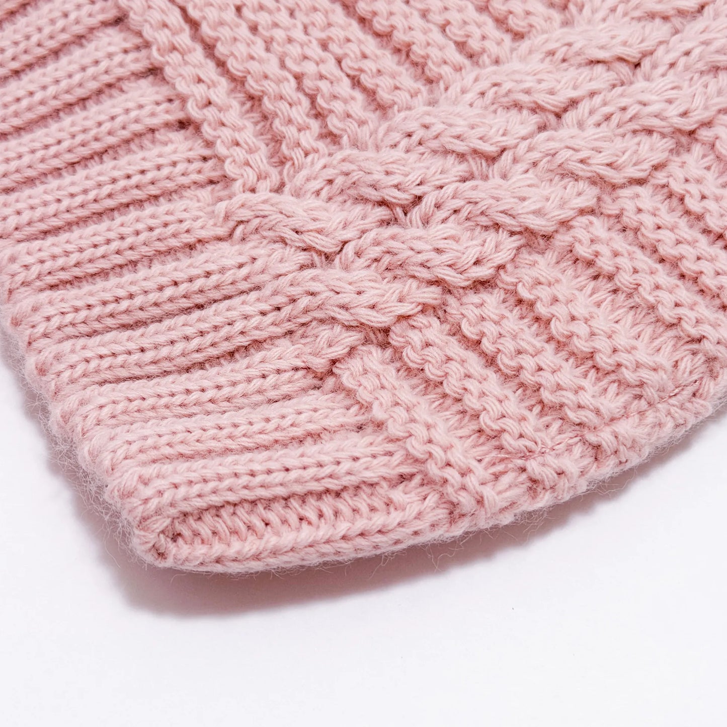 Pormenor de gorro de malha tricotada com pompom rosa