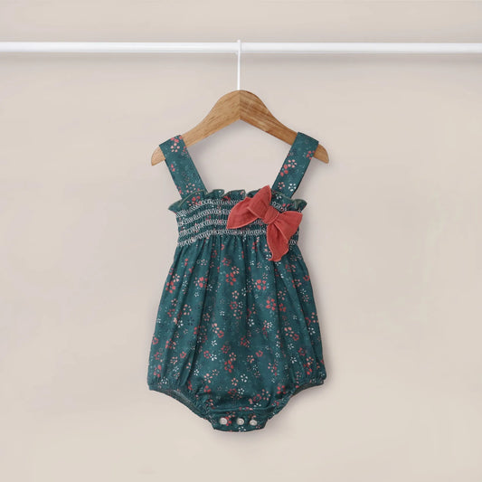 Jardineira de menina verde com padrão florido e laço no peito coral em contraste