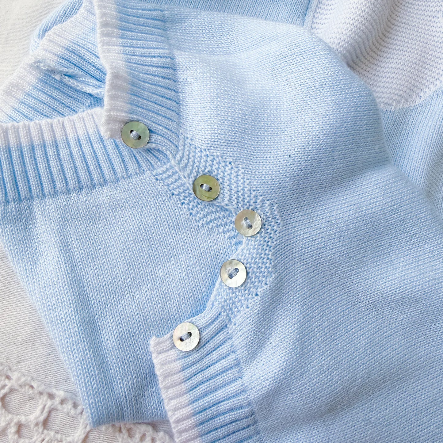 Pormenor de macacão em malha com gola Peter Pan e motivo ursinho azul