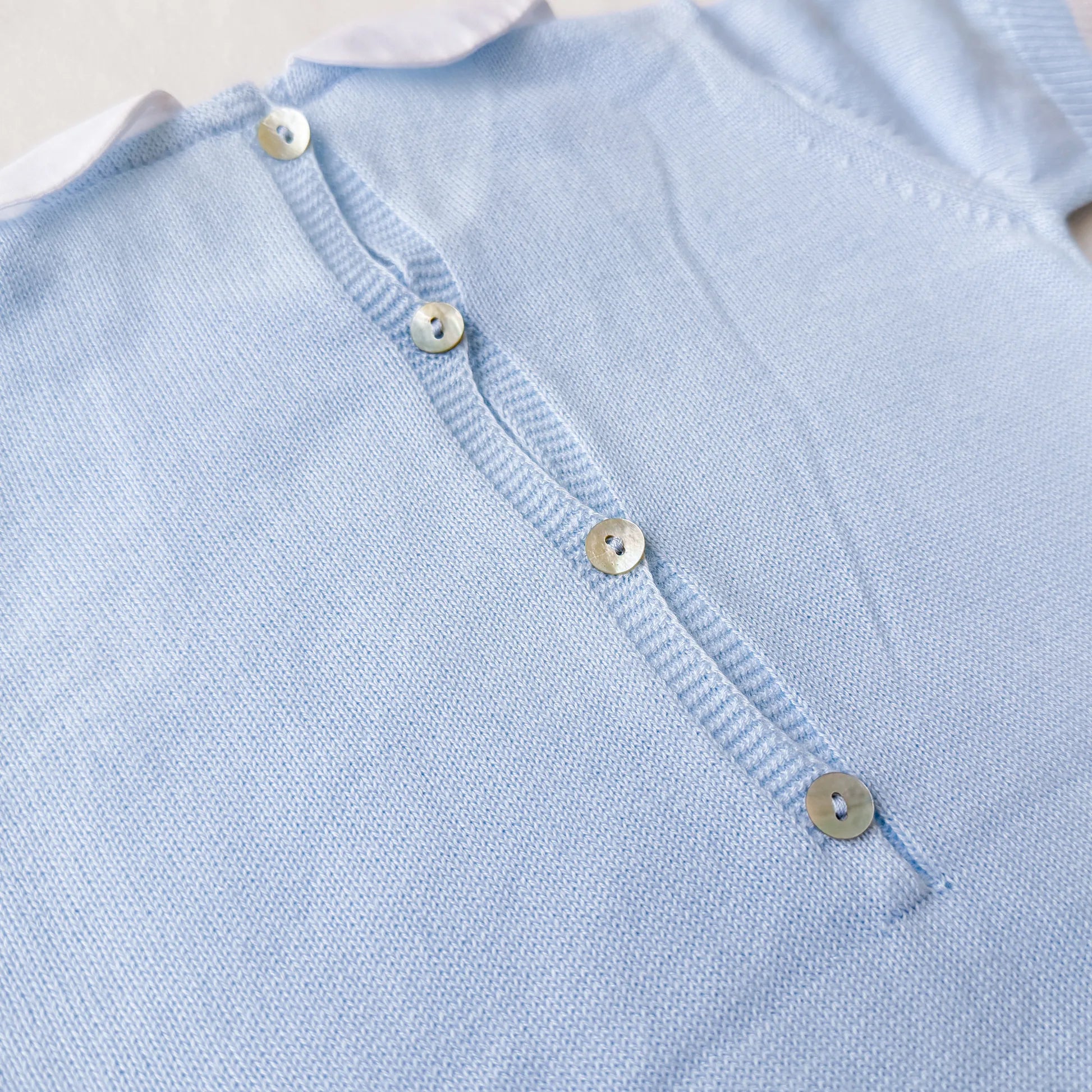 Pormenor de macacão em malha com gola Peter Pan e motivo ursinho azul