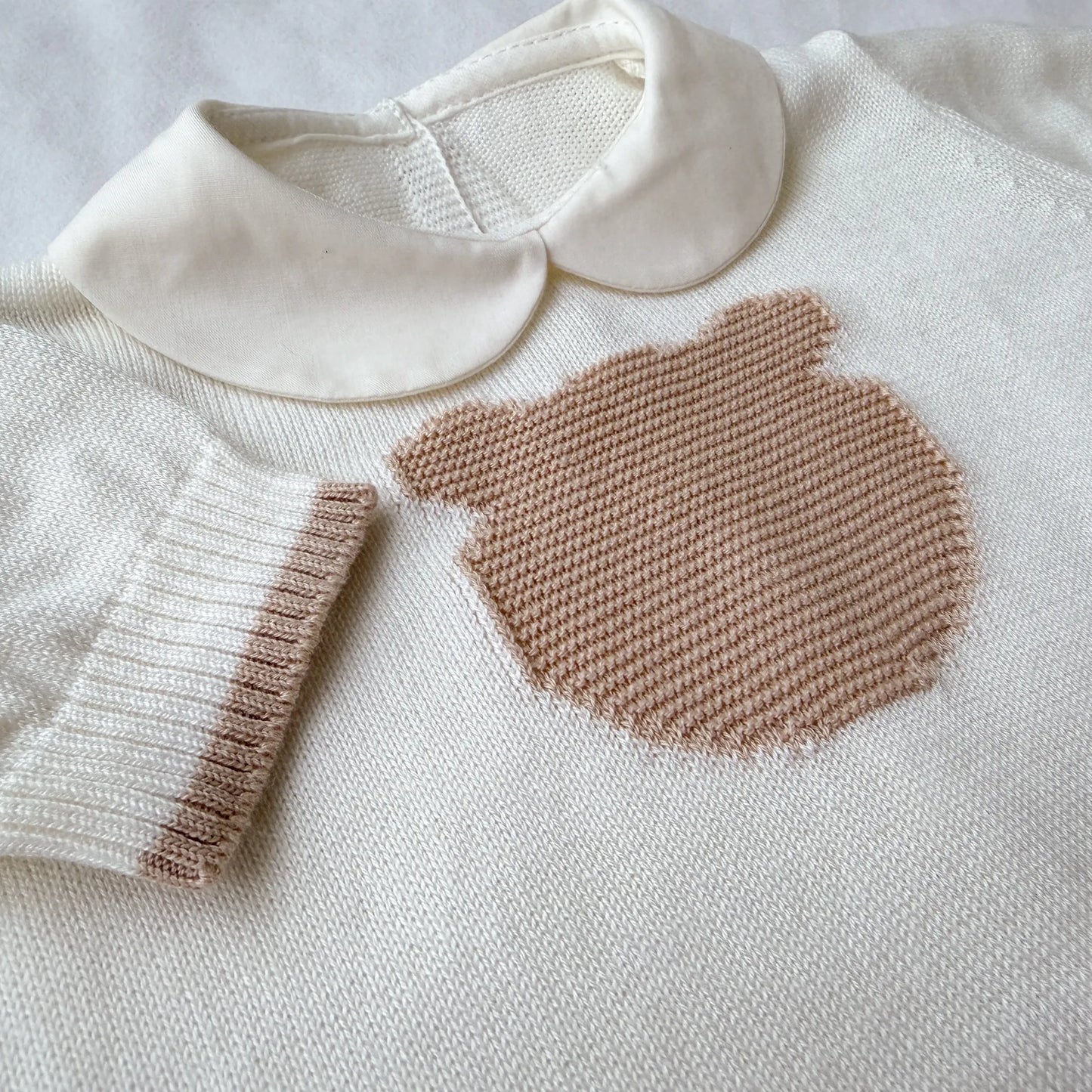 Pormenor de macacão em malha com gola Peter Pan e motivo ursinho pérola