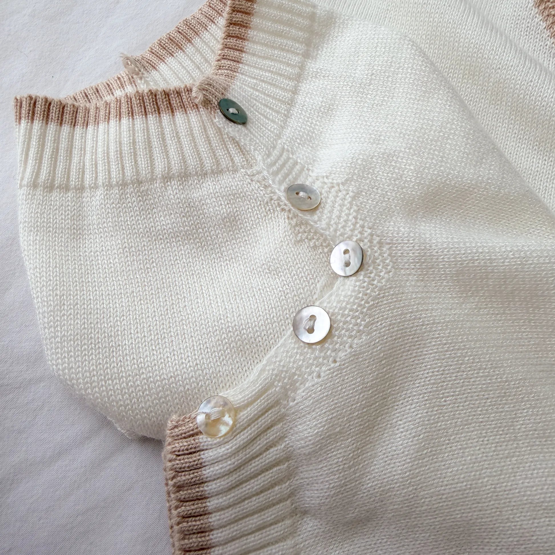Pormenor de macacão em malha com gola Peter Pan e motivo ursinho pérola