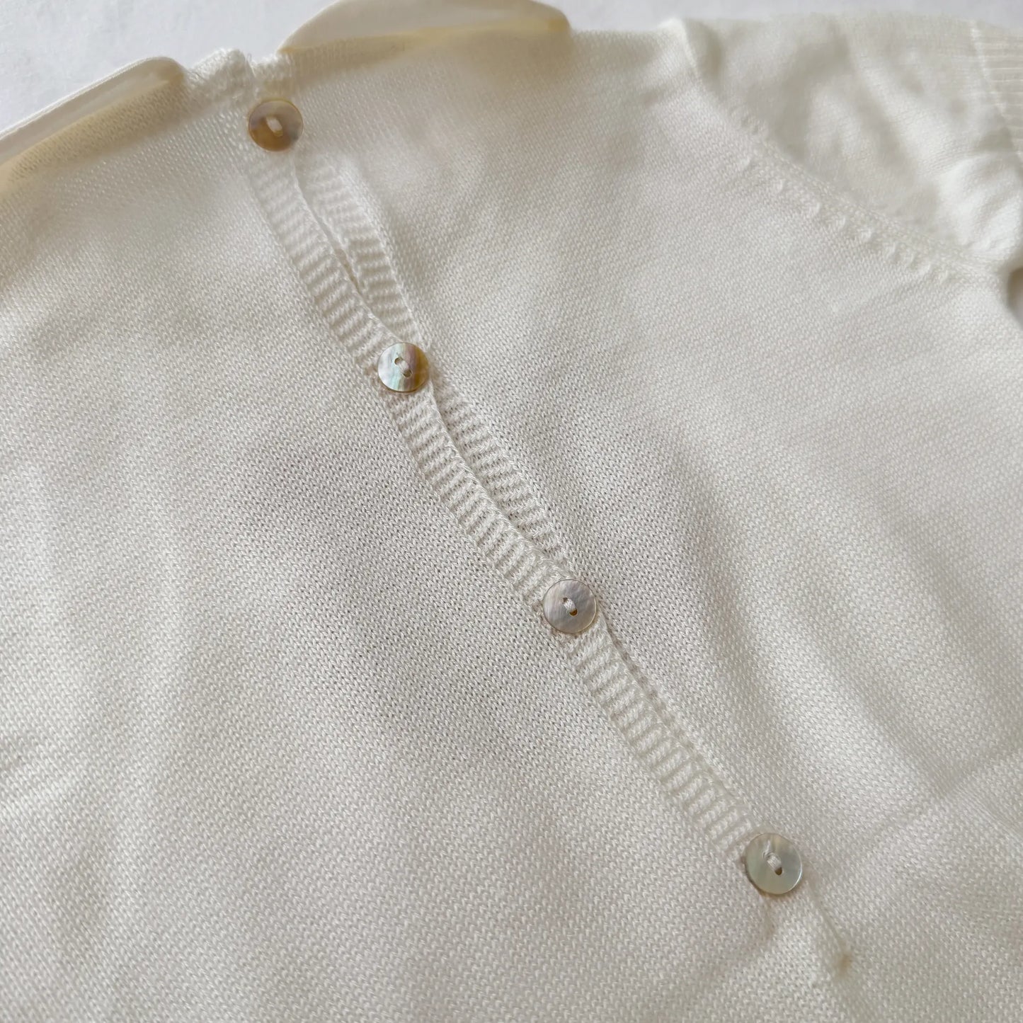 Pormenor de macacão em malha com gola Peter Pan e motivo ursinho pérola