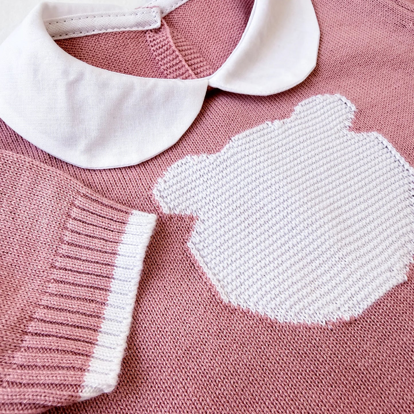 Pormenor de macacão em malha com gola Peter Pan e motivo ursinho rosa