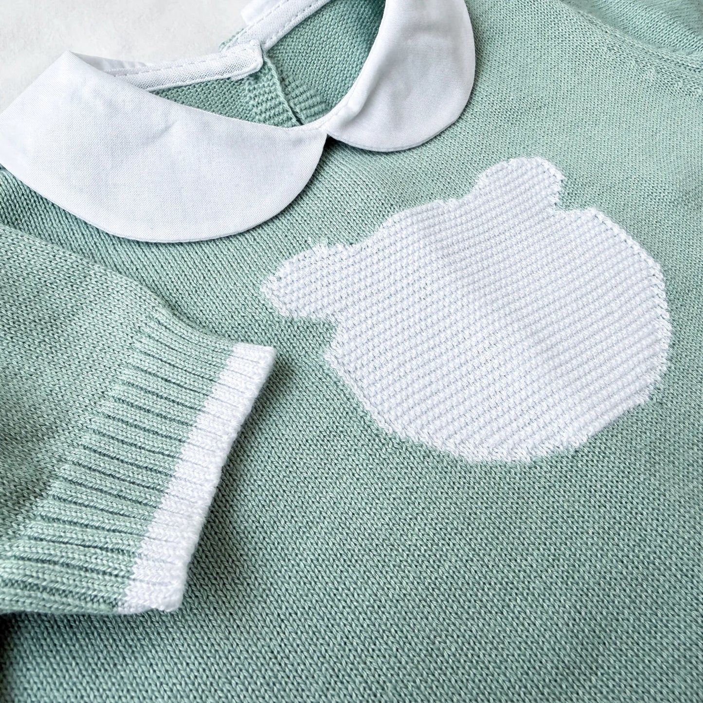 Pormenor de macacão em malha com gola Peter Pan e motivo ursinho verde