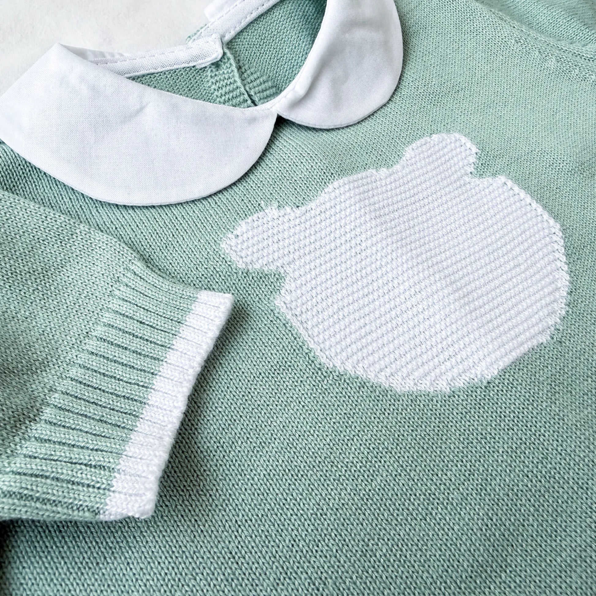 Pormenor de macacão em malha com gola Peter Pan e motivo ursinho verde