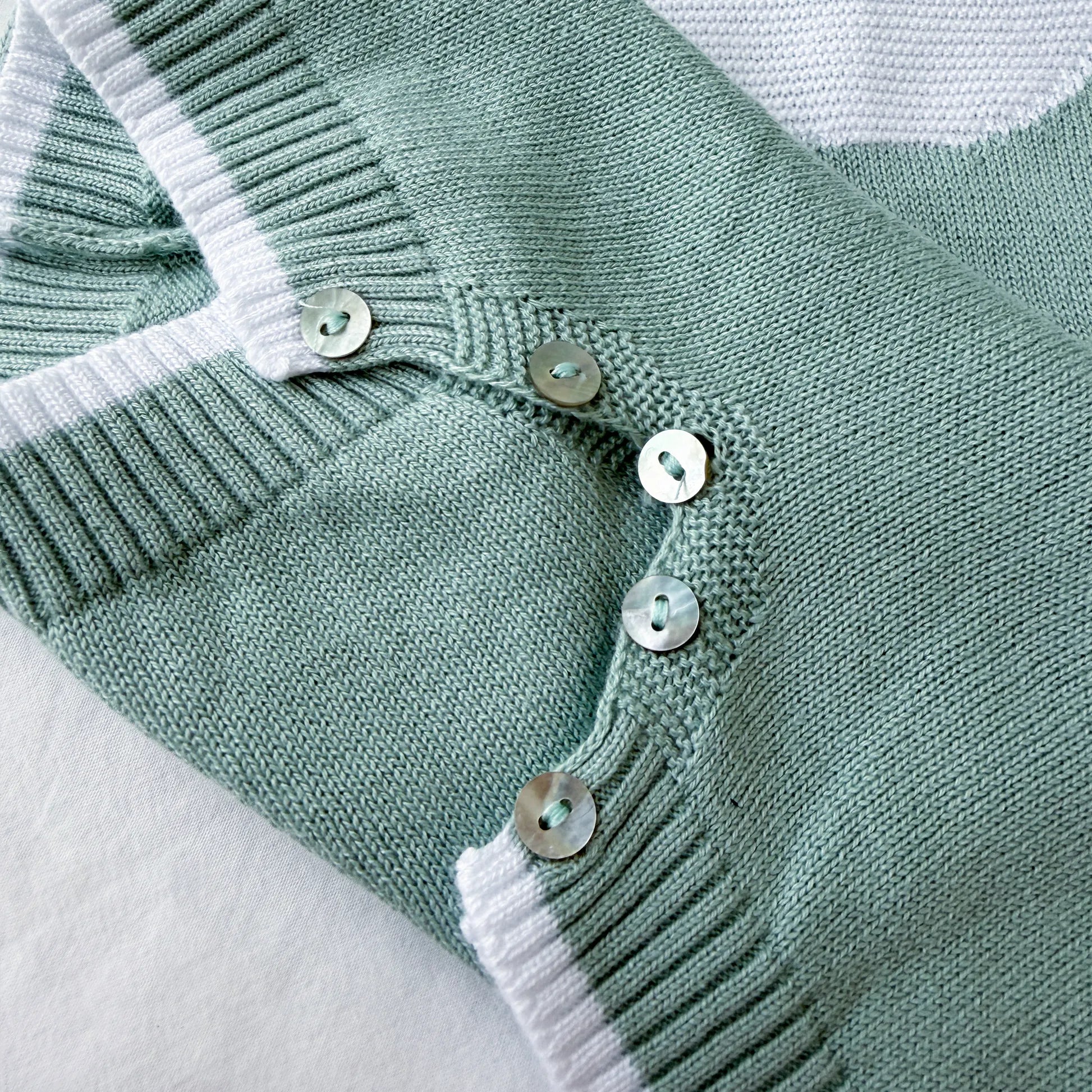 Pormenor de macacão em malha com gola Peter Pan e motivo ursinho verde