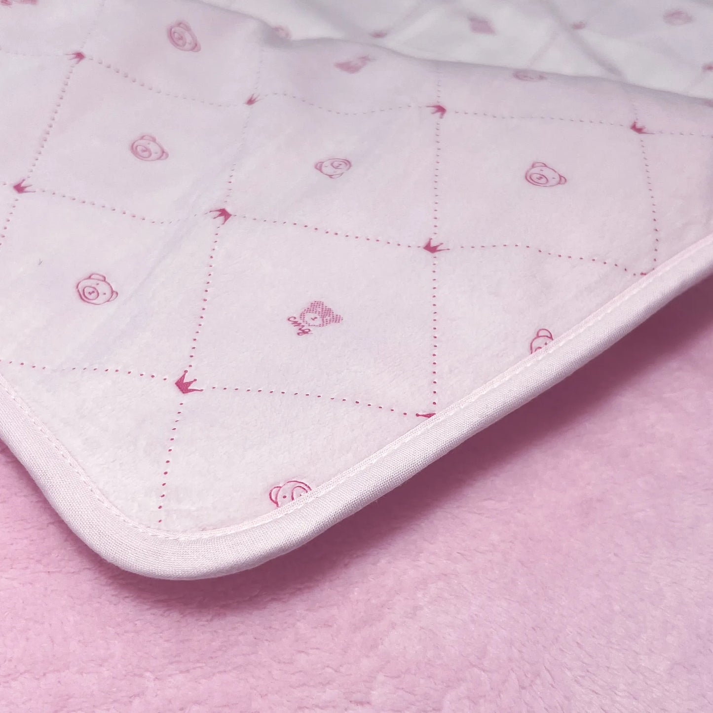 Pormenor de manta dupla face com estampado de ursinhos e losangos de um lado rosa