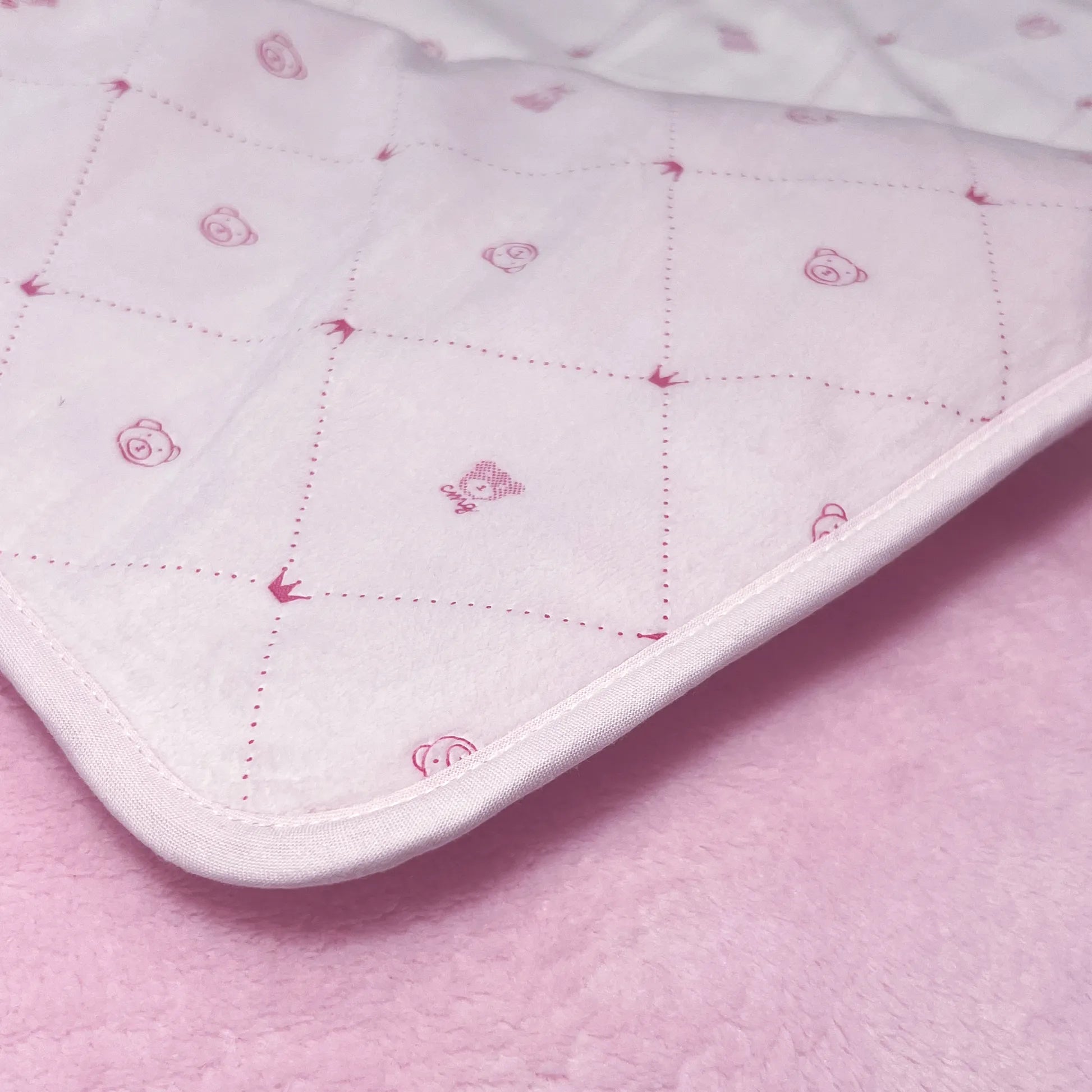 Pormenor de manta dupla face com estampado de ursinhos e losangos de um lado rosa