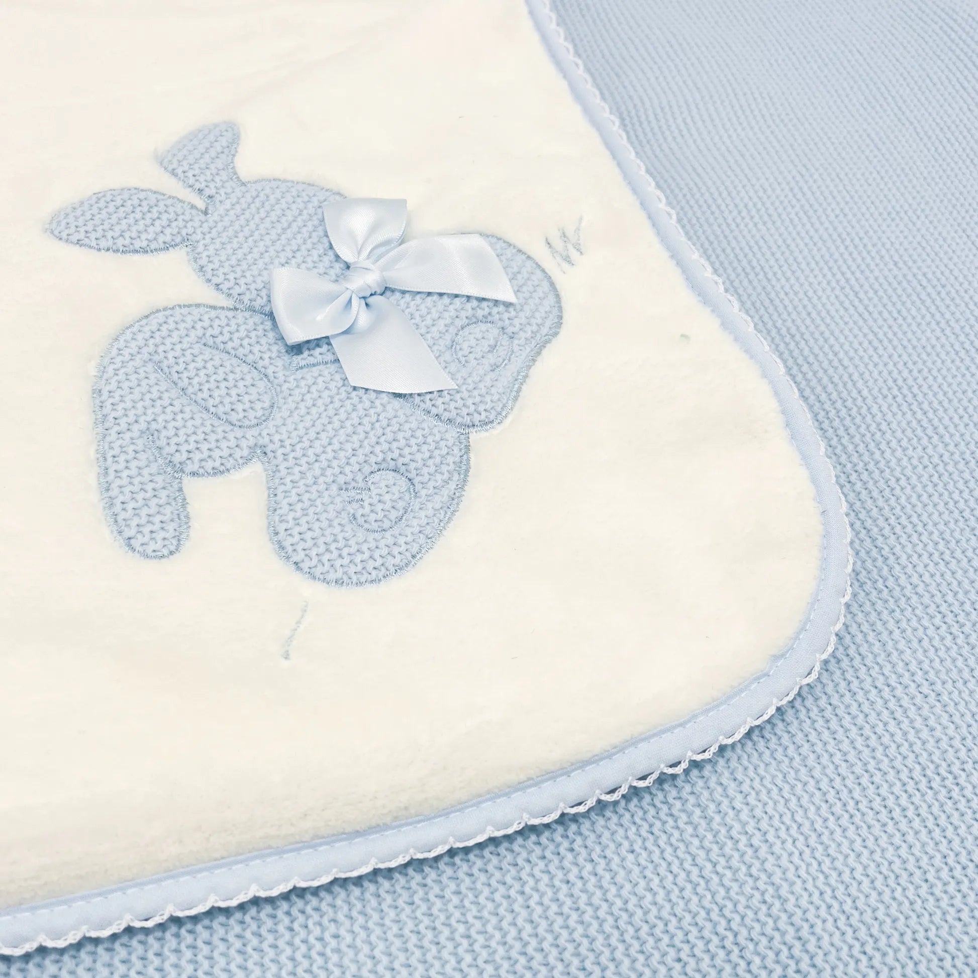 Pormenor de manta com motivo coelhos tricot com laço azul