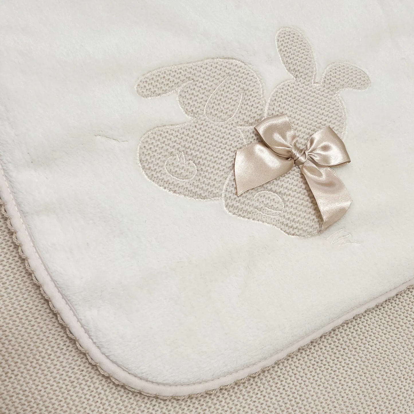 Pormenor de manta com motivo coelhos tricot com laço bege
