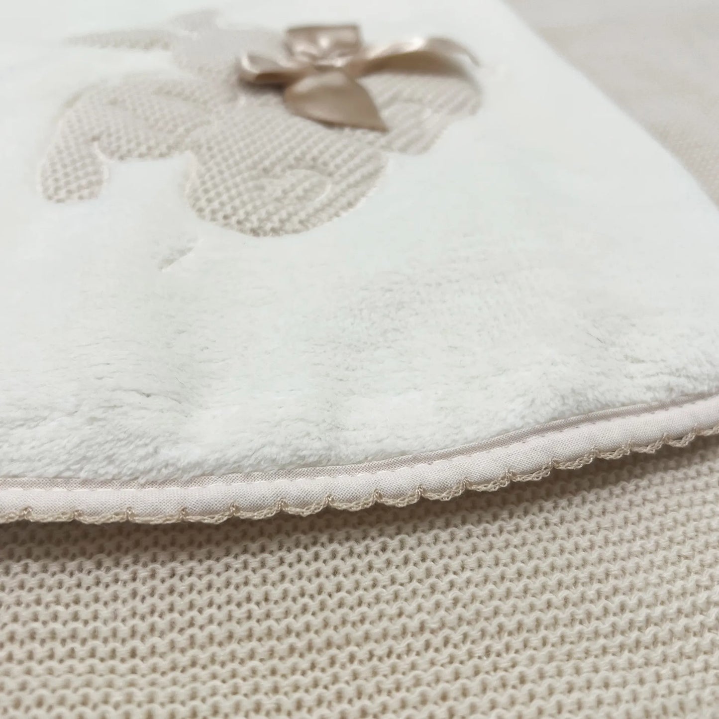 Pormenor de manta com motivo coelhos tricot com laço bege