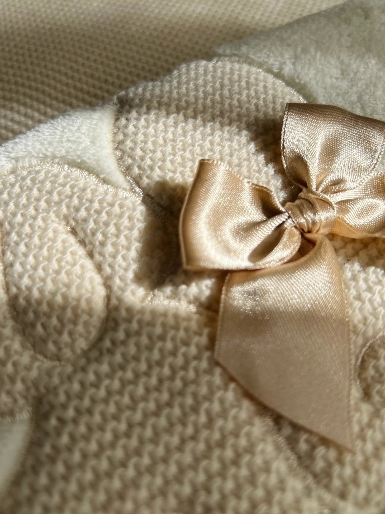 Pormenor de manta com motivo coelhos tricot com laço bege