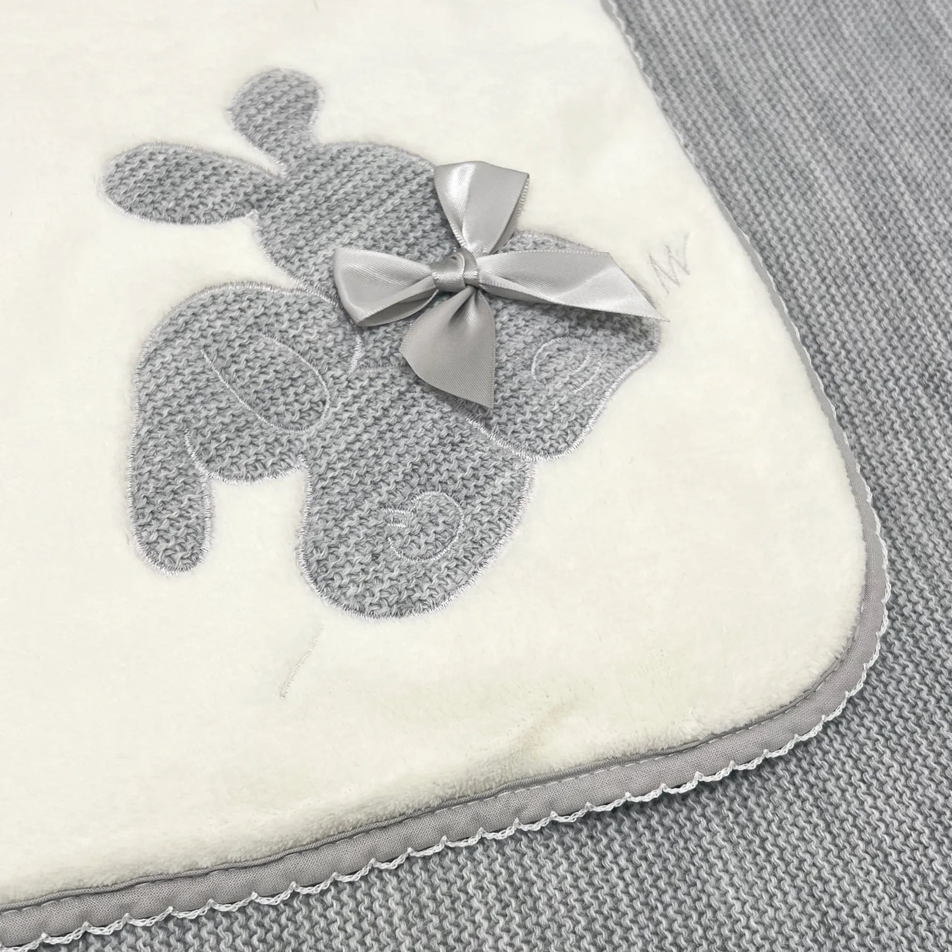 Pormenor de manta com motivo coelhos tricot com laço cinza