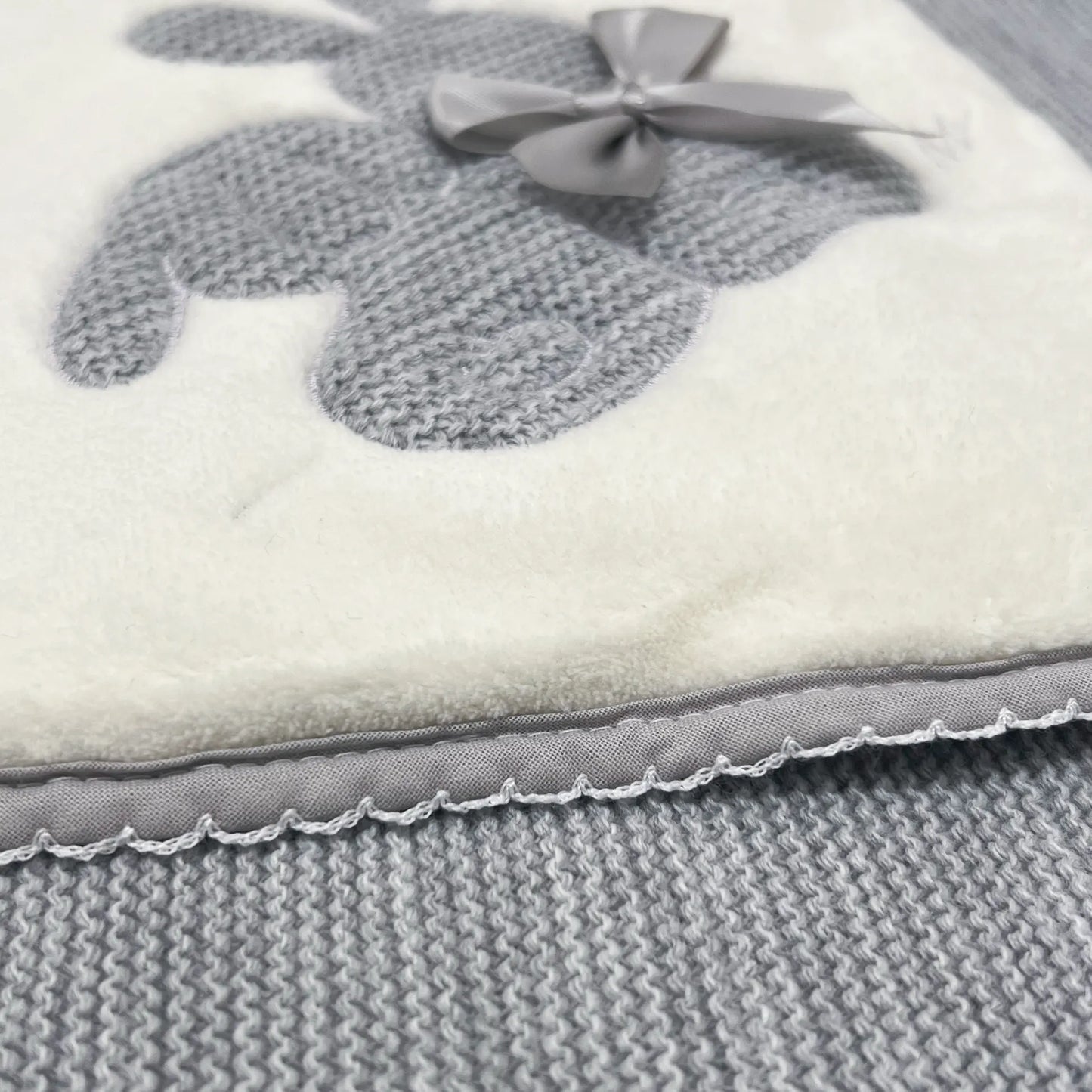 Pormenor de manta com motivo coelhos tricot com laço cinza