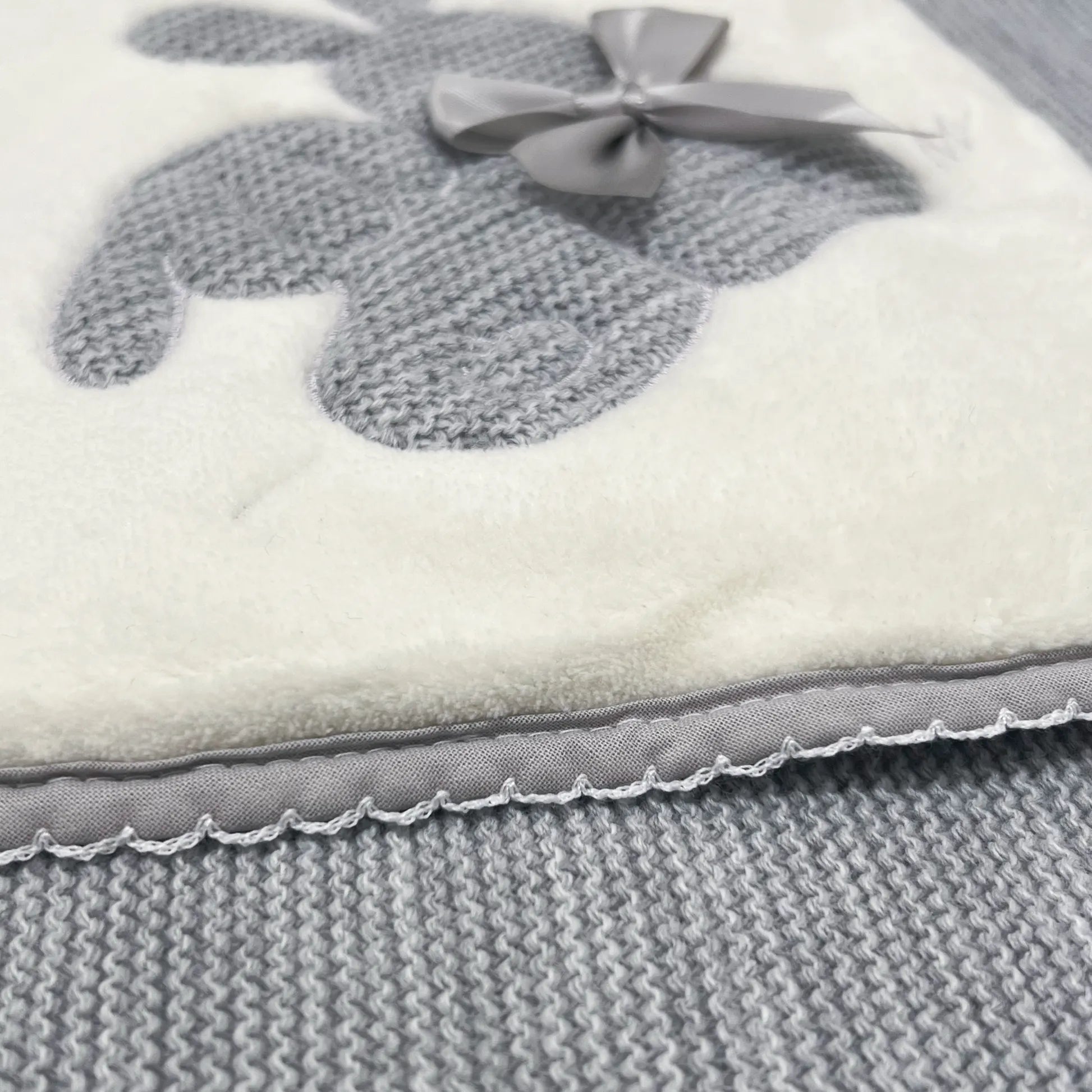 Pormenor de manta com motivo coelhos tricot com laço cinza