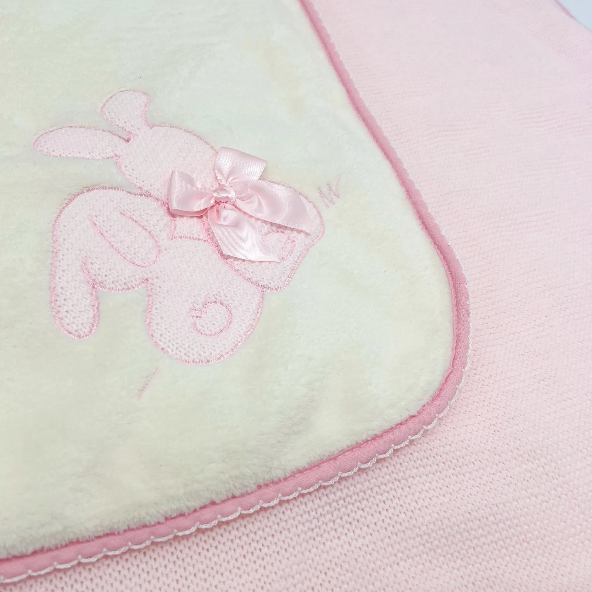 Pormenor de manta com motivo coelhos tricot com laço rosa