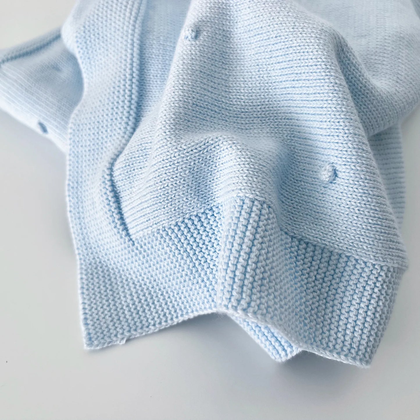 Pormenor de manta em tricot com relevo de pompons azul