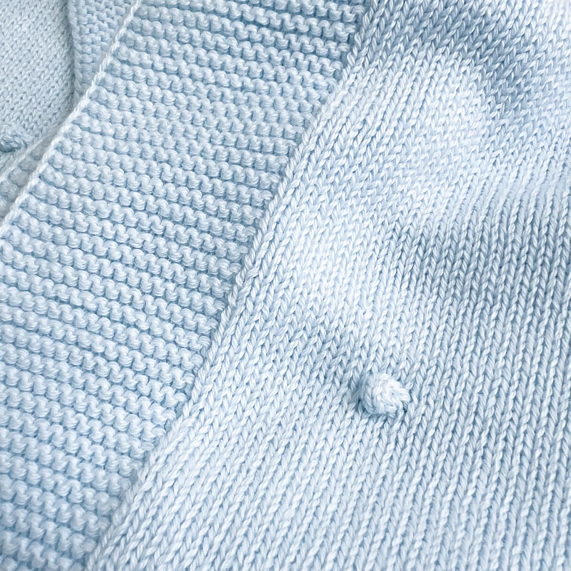 Pormenor de manta em tricot com relevo de pompons azul