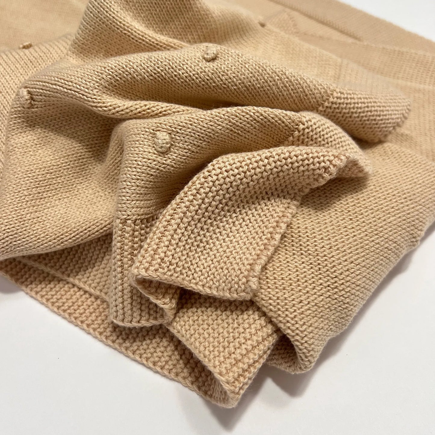Pormenor de manta em tricot com relevo de pompons bege