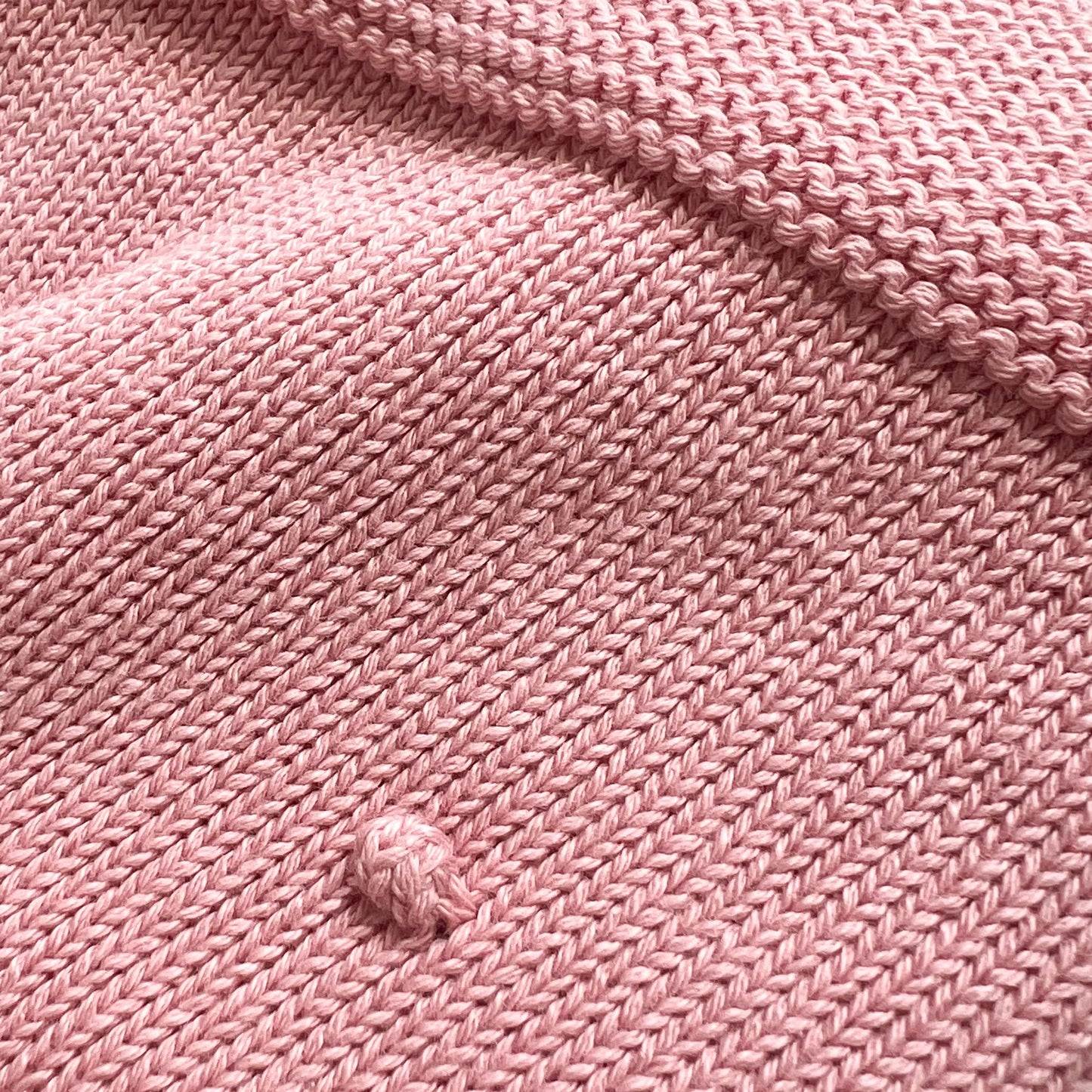 Pormenor de manta em tricot com relevo de pompons rosa