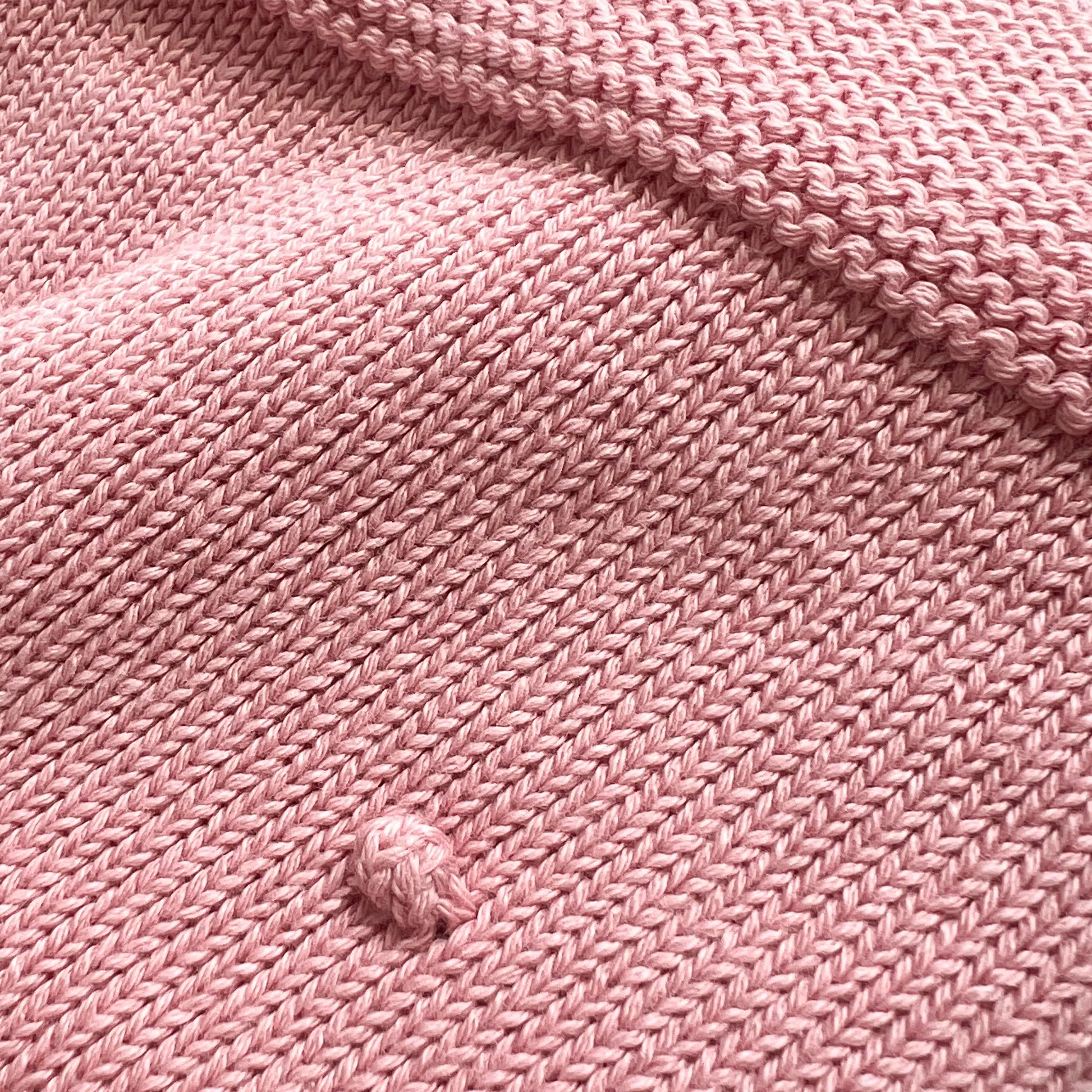 Pormenor de manta em tricot com relevo de pompons rosa
